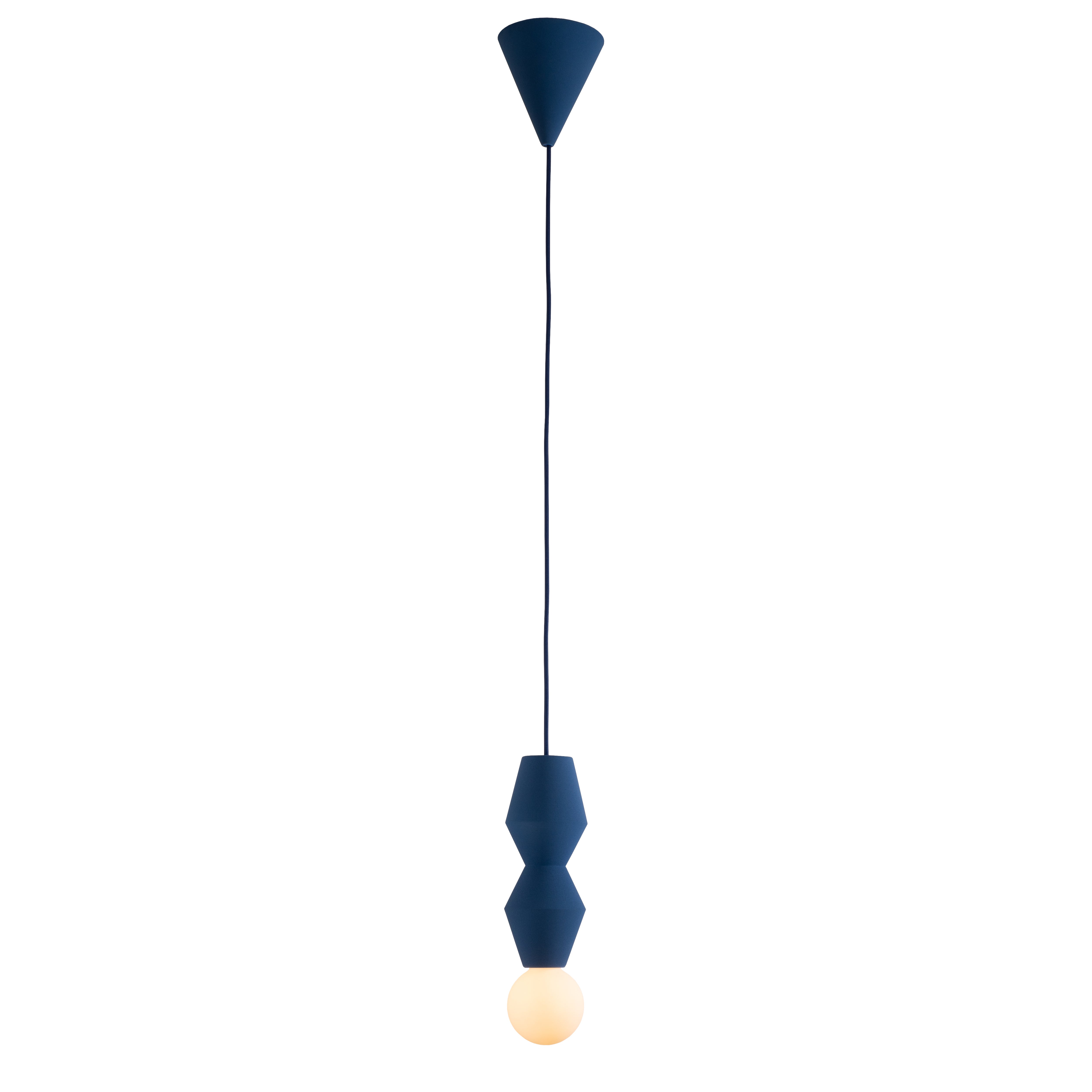 The Schneid Stucco No. II pendant light boasts a dark blue geometric ceramic design with an elegant bulb at the bottom. Its minimalist look is completed by a long, slender cord connecting to a matching ceiling mount.