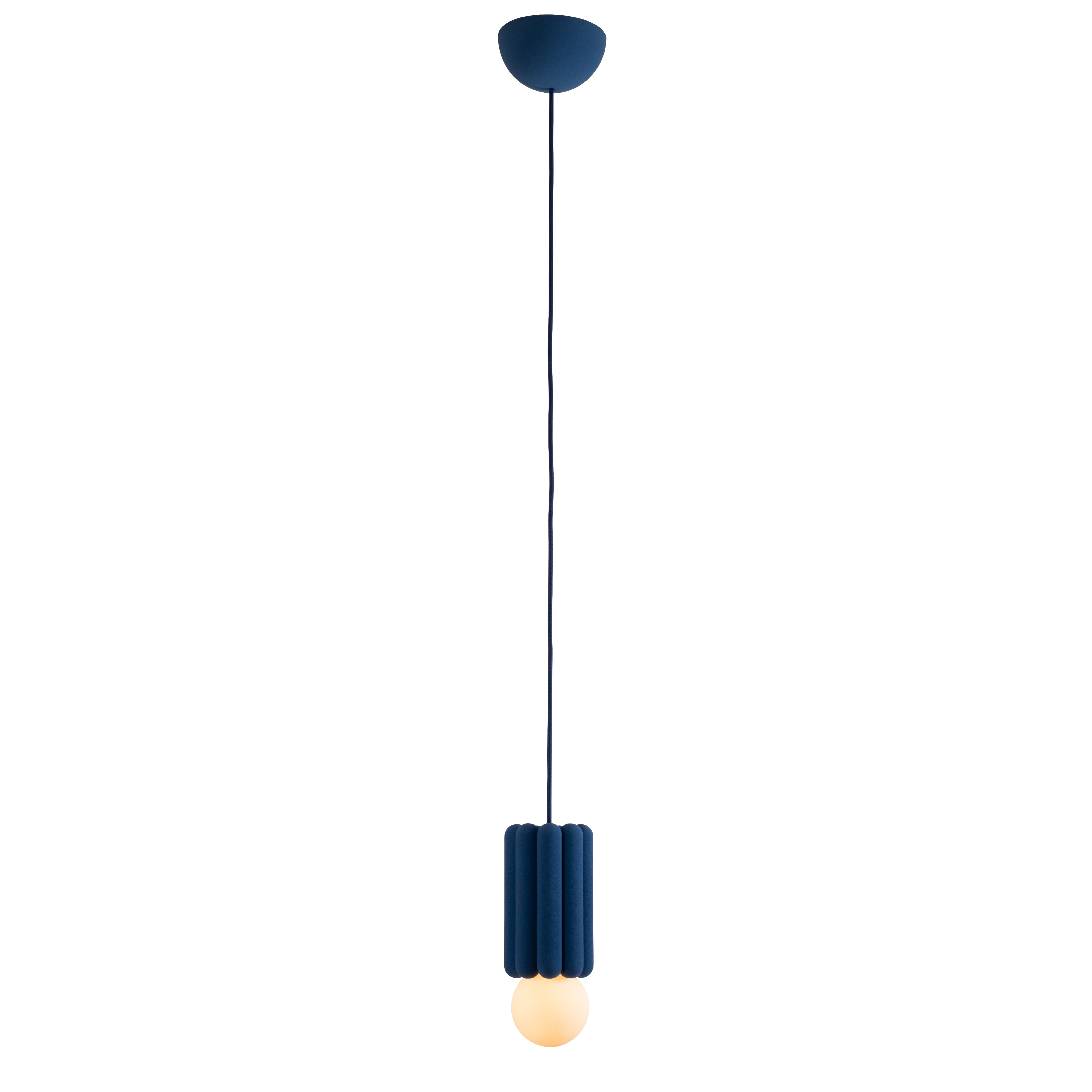 The Stucco No. III by Schneid is a modern pendant light resembling a sculpture, with a dark blue fluted cylindrical housing. It hangs from a matching cord and exposes the bulb at the bottom, offering creative luminosity through its soft glow.