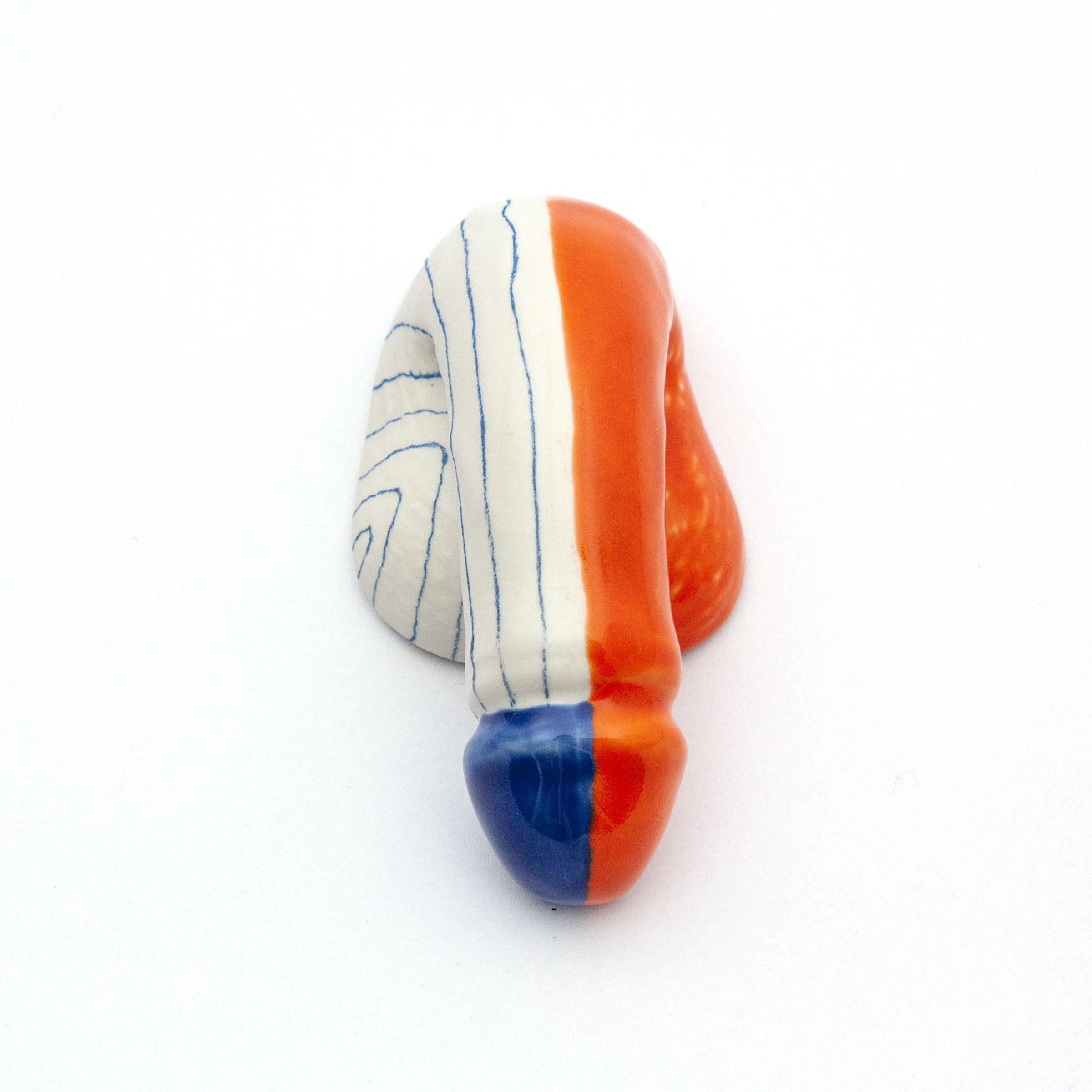 The A Decorative Sex - Go Mets by Schwanzmanufaktur is a handmade Austrian ceramic sculpture featuring a phallic shape with vertical stripes, showcasing white with blue lines on one side and solid orange transitioning to blue on the other, against a plain white background.