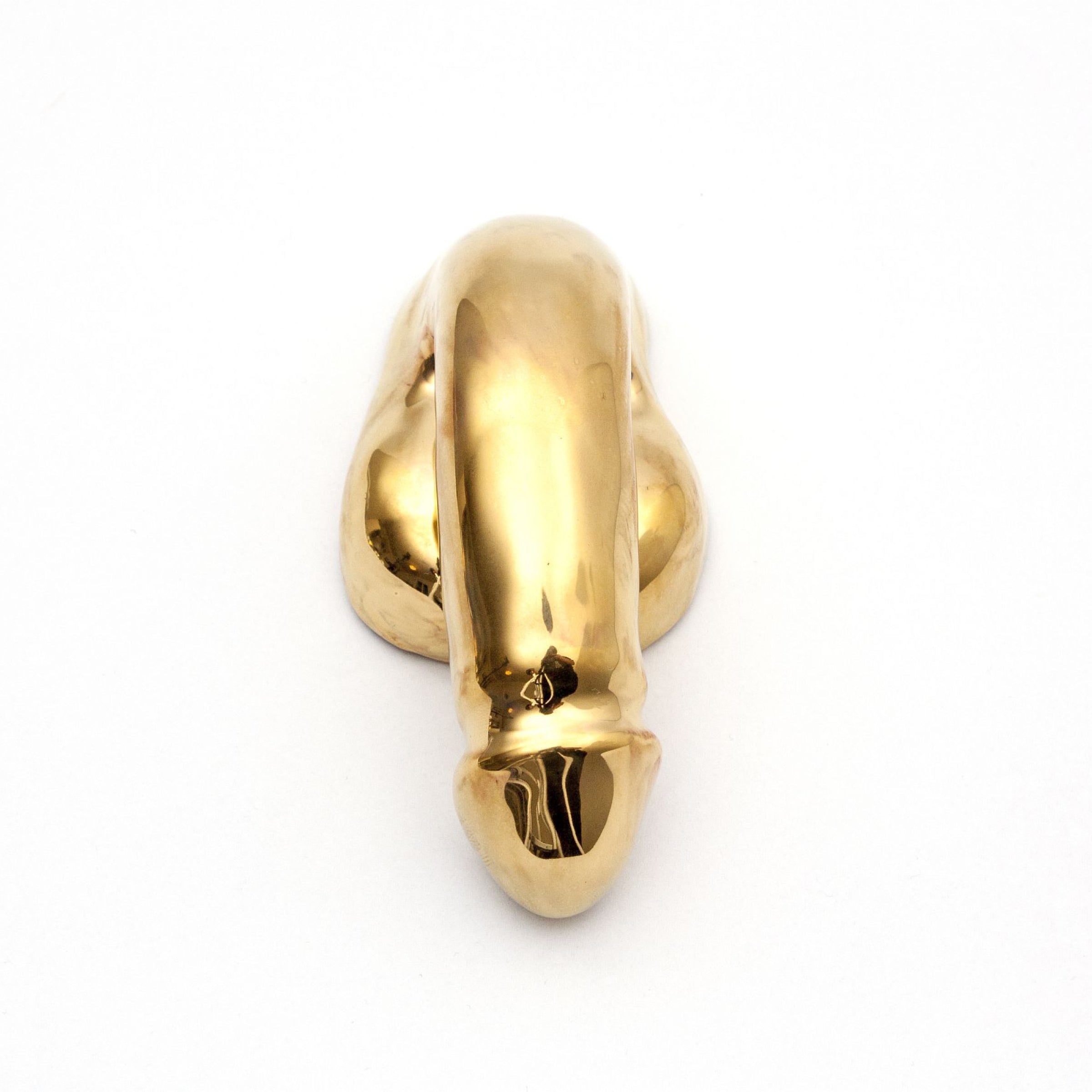 The A Decorative Sex - Gold by Schwanzmanufaktur is a shiny, gold-colored sculpture in an abstract, phallic shape set against a plain white background.