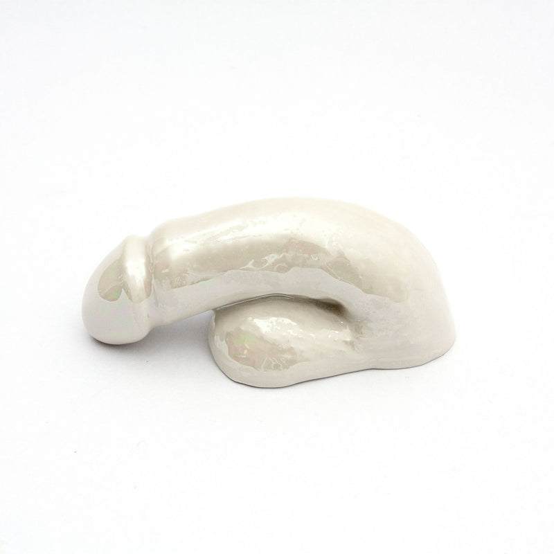 The A Decorative Sex - Pearl by Schwanzmanufaktur is a glossy white ceramic sculpture with an elongated form, subtle curvature, and rounded edges. Showcasing Austrian craftsmanship, this handmade porcelain piece is ideal as decorative wall art against a plain white background.