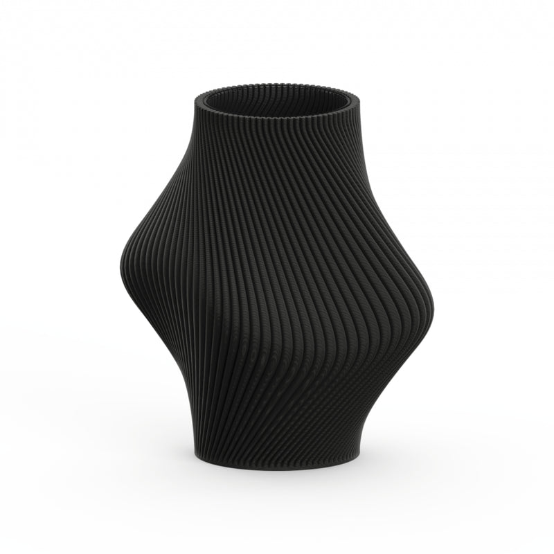 The Bloz 138g Vase by Sheyn is a black, intricately ribbed vase with a symmetrical, curvy design produced through eco-friendly 3D printing. Its textured surface forms a spiral pattern, tapering elegantly at the top and bottom against a plain white background.