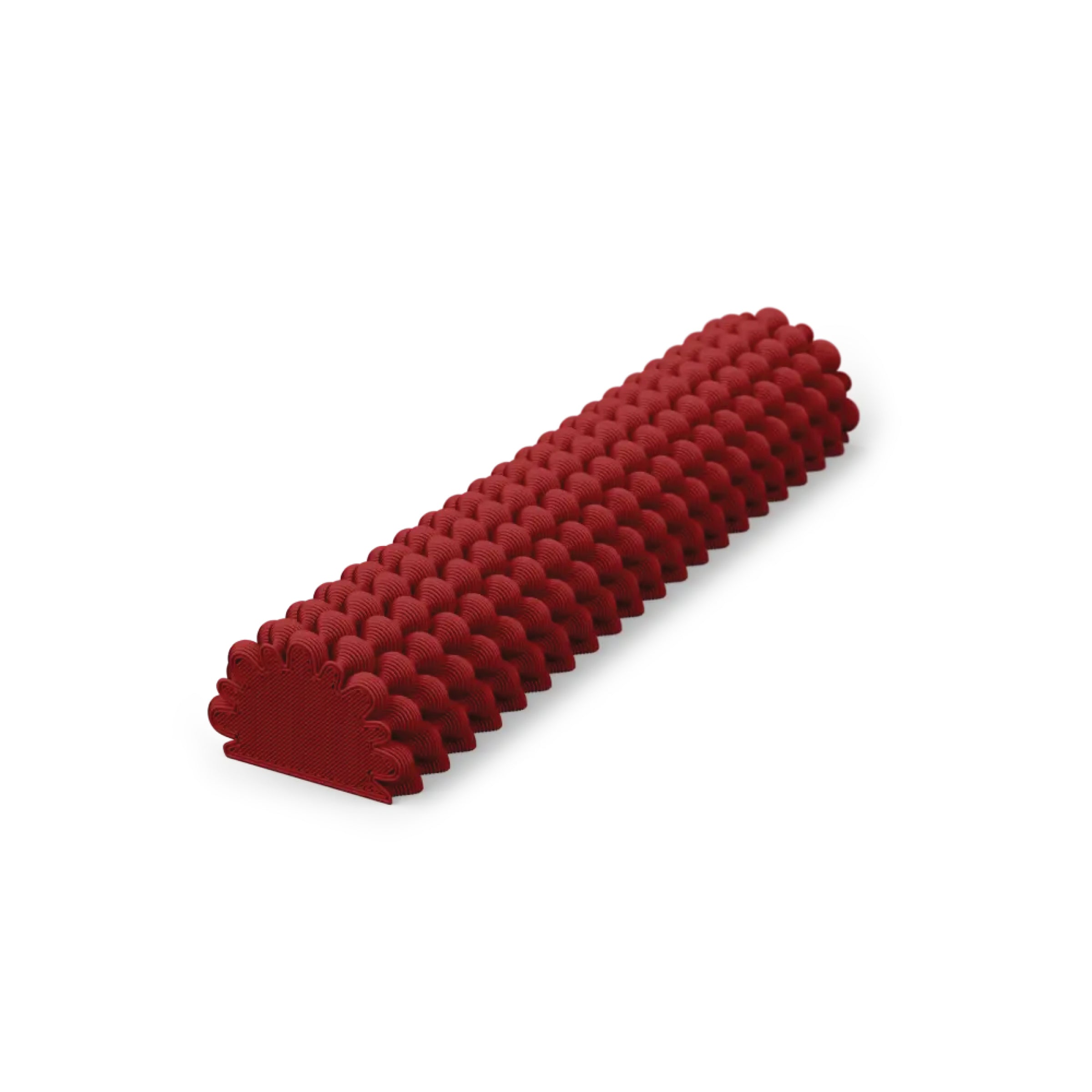 A red silicone baking mold shaped like a semicircular tube features a textured, scalloped design reminiscent of Sheyns Hoyt 29g Mezuzah style. It rests against a plain white background, showcasing intricately detailed craftsmanship akin to 3D printing precision.