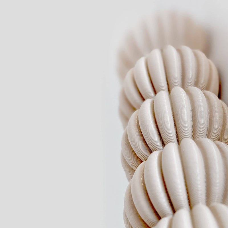 Close-up of the Zayl 30g Mezuzah by Sheyn, showcasing its textured, spiral-pattern reminiscent of a twisted rope or shell. Crafted from an ecological compound, its soft beige hue contrasts elegantly with the plain light gray background.
