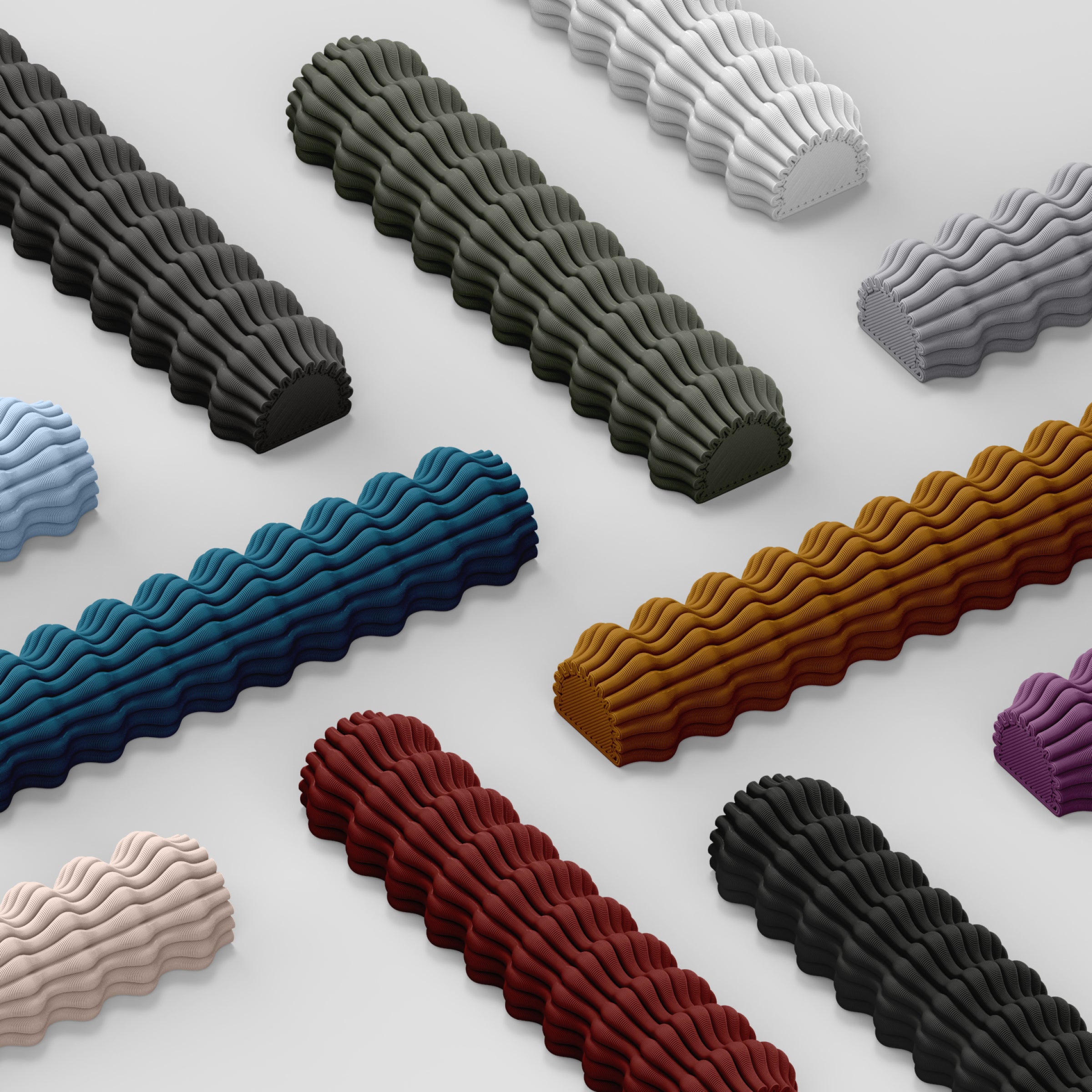 Diagonal rows of Zayl 30g Mezuzah by Sheyn, crafted from an eco-friendly compound in colors like blue, red, and gray, rest on a white background. Each features a wavy ribbed surface with intricate detail similar to 3D printing.