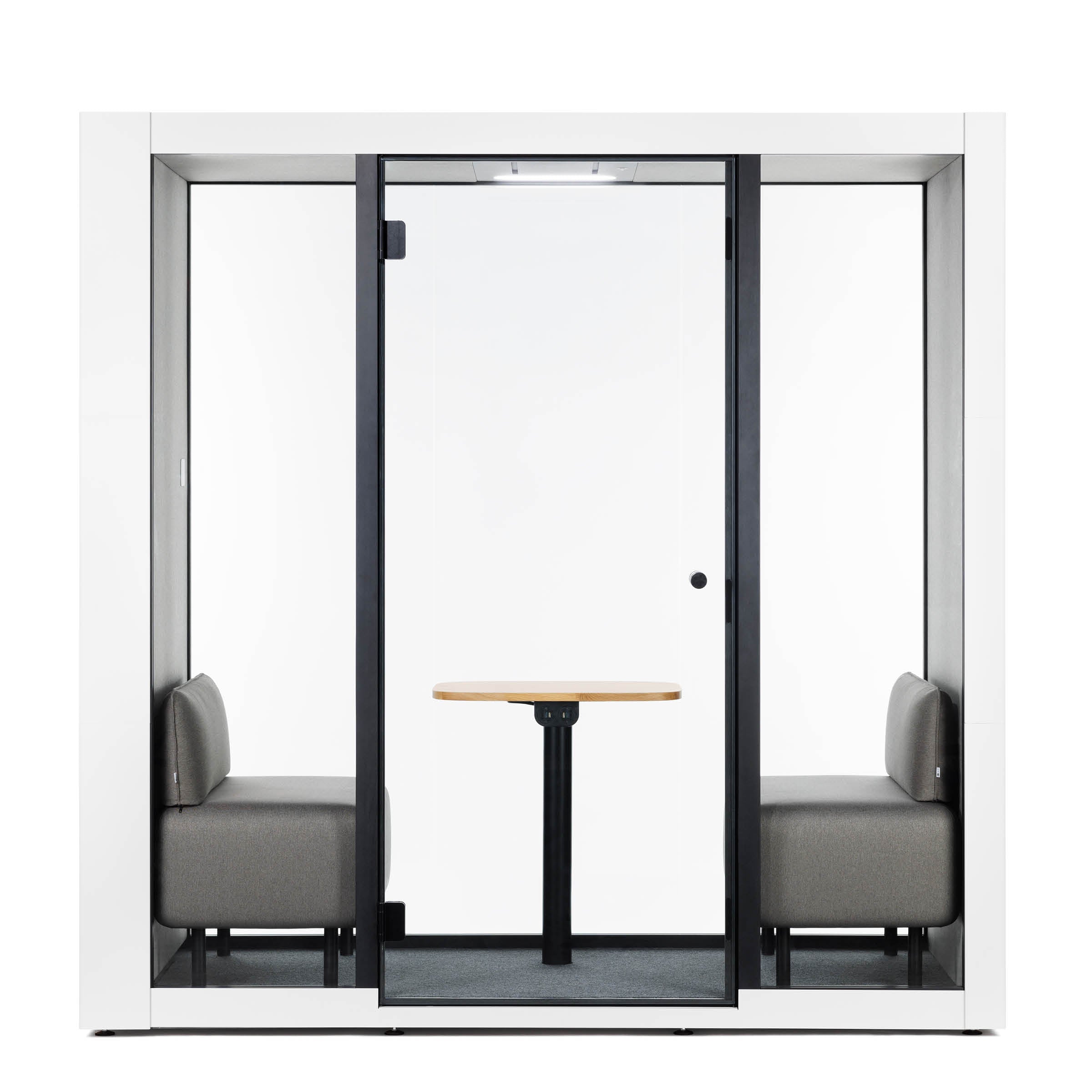 The SilentLab OFFICE POD SPARK 2 features glass walls, two gray upholstered benches facing each other with a small wooden table in between, all enclosed in a sleek white and black frame to enhance working conditions by reducing ambient noise.