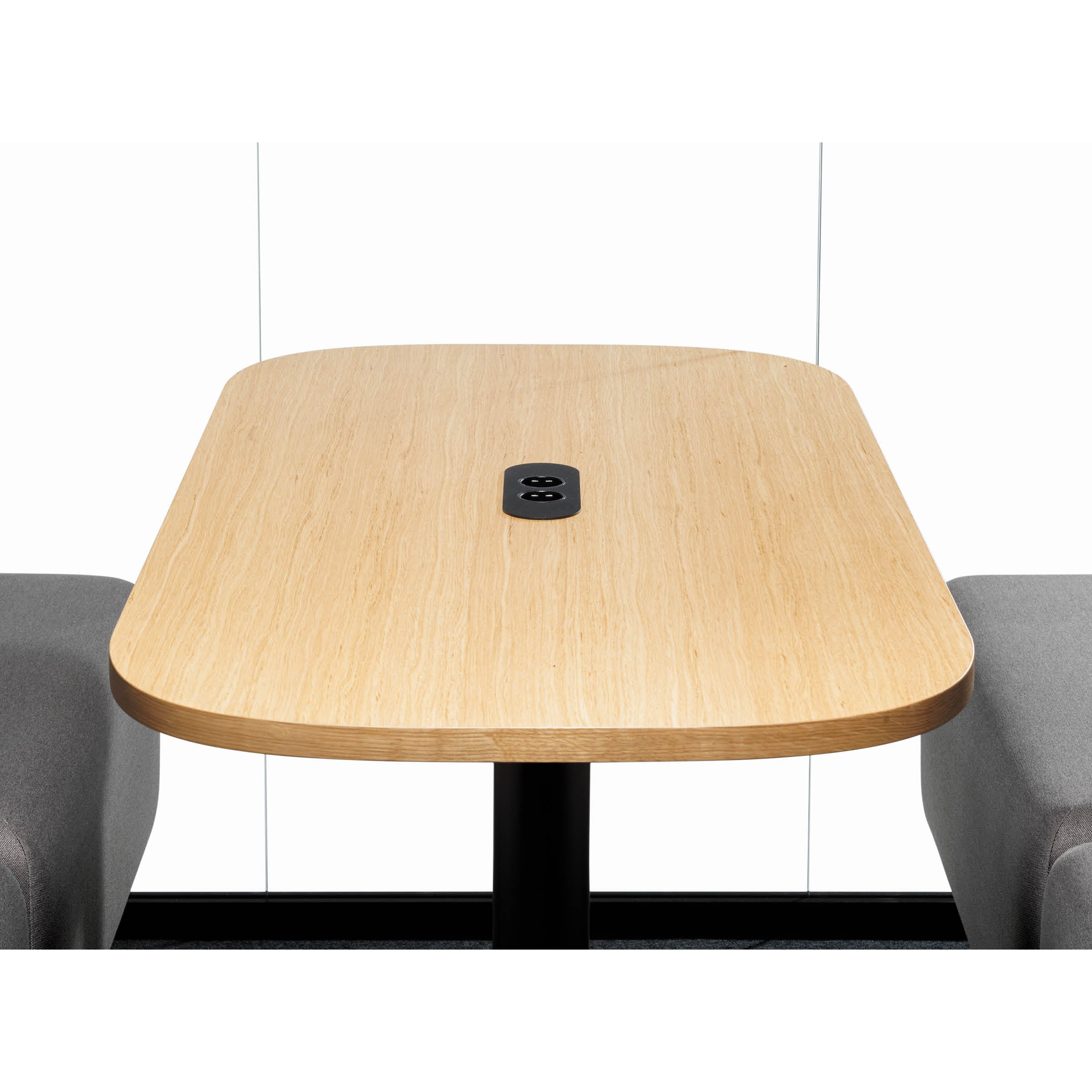 The OFFICE POD SPARK 4 by SilentLab features a rectangular light wood table with rounded edges, a central black power outlet, gray upholstered benches, and is ideal for private meetings against a crisp white wall.