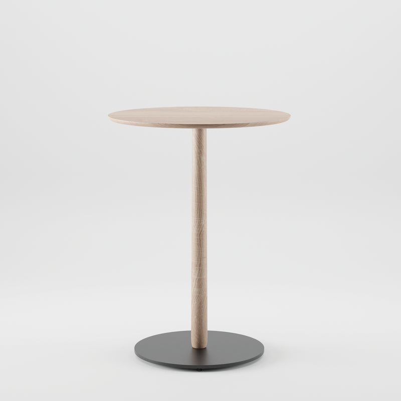 The Artisan Bistro B Table is a minimalist round wooden table with a single central leg and a circular black base. Crafted from solid wood using eco-friendly materials, it stands elegantly against a plain white background.