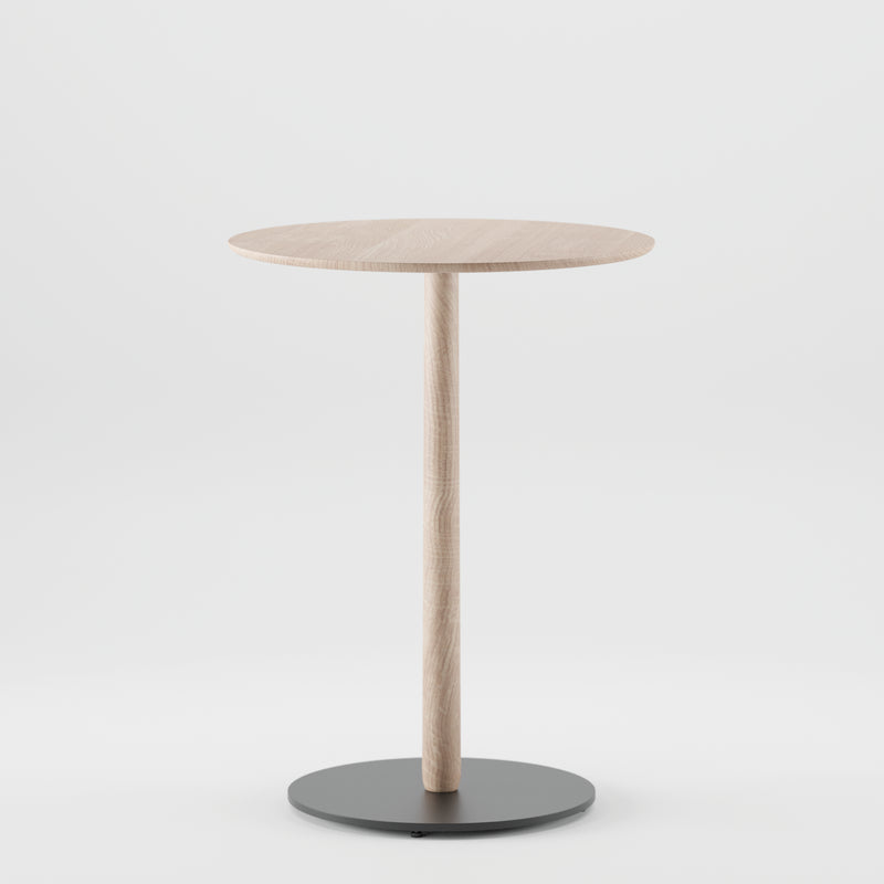 The Artisan Bistro B Table, a minimalist piece, boasts a round wooden top made from solid wood with natural oil finish. It features a thin central column and a black circular base, all set elegantly against a plain white background.