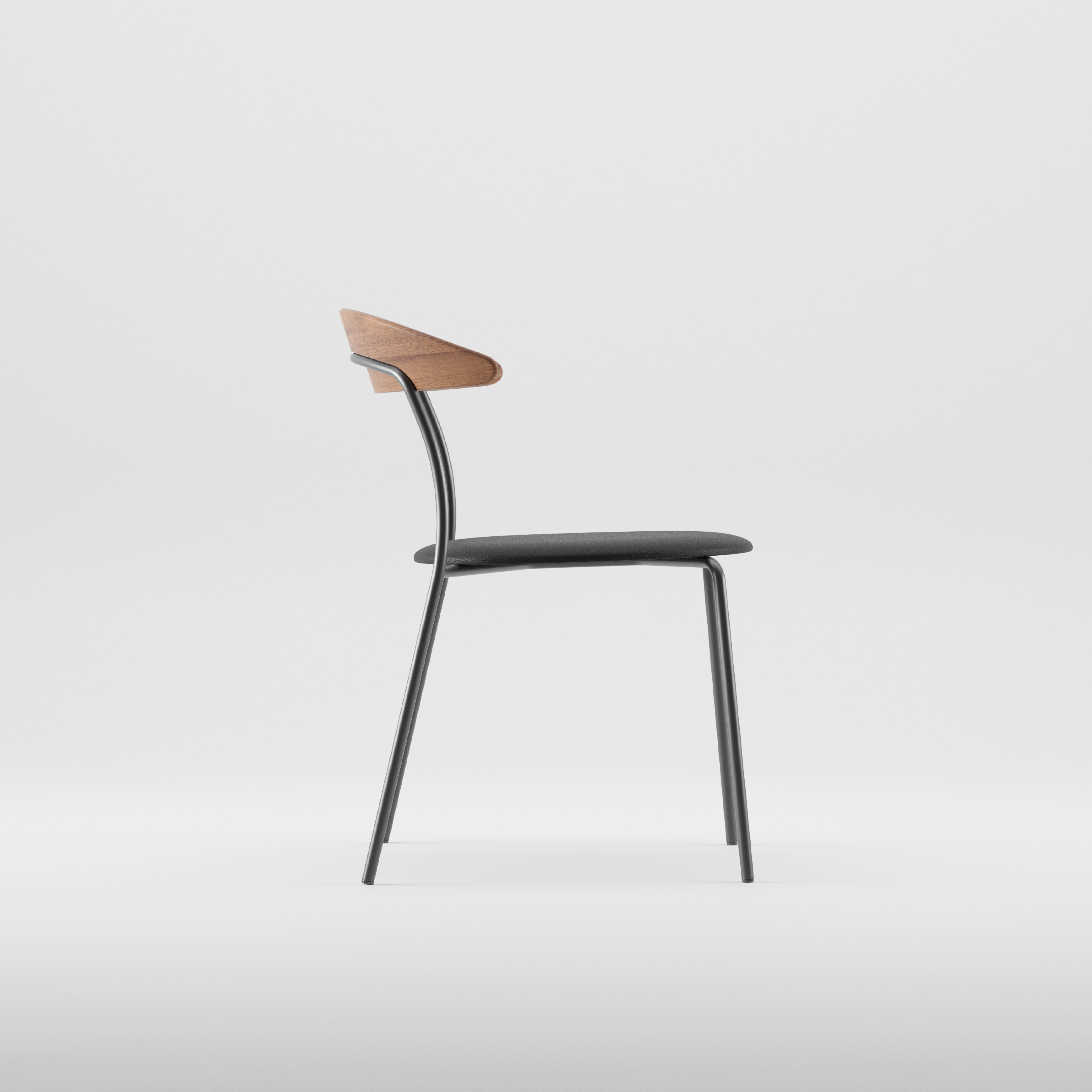 The KINU Chair by Artisan is a minimalist piece with a black seat, metal legs, and an eco-friendly solid wood backrest. It is elegantly displayed from the side against a light-colored background.