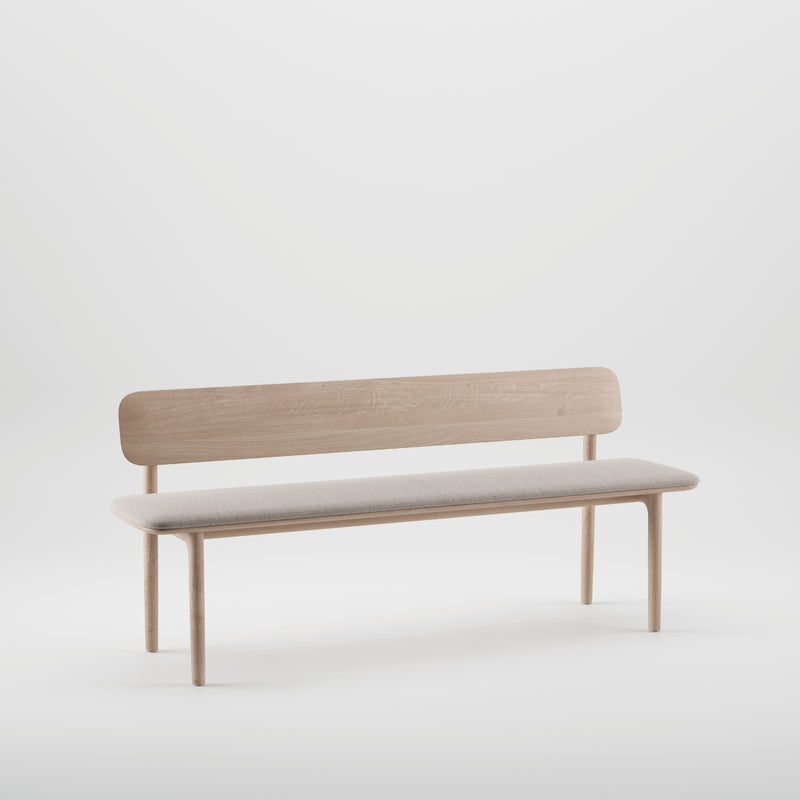 The NEVA Bench with backrest by Artisan is a minimalist piece featuring a light fabric cushion and simple backrest. Crafted by artisan carpenters with clean lines, it stands against a plain white background for an elegant effect.
