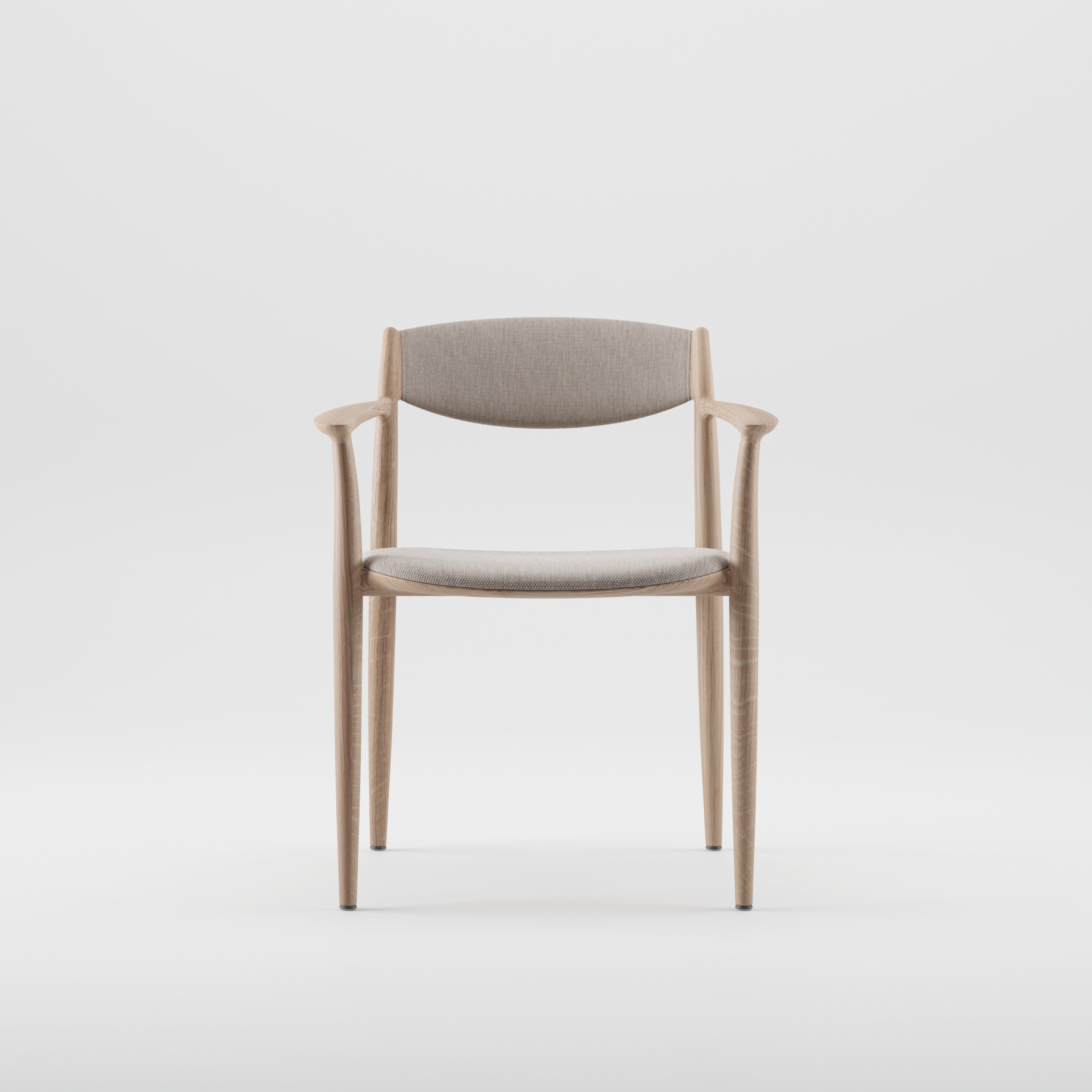 The NILA Chair by Artisan is a minimalist wooden chair made from solid wood. It features a light grey cushioned seat and backrest, sleek curved armrests, and tapered legs. Highlighting its environmentally-friendly materials, it stands out against a plain white background.