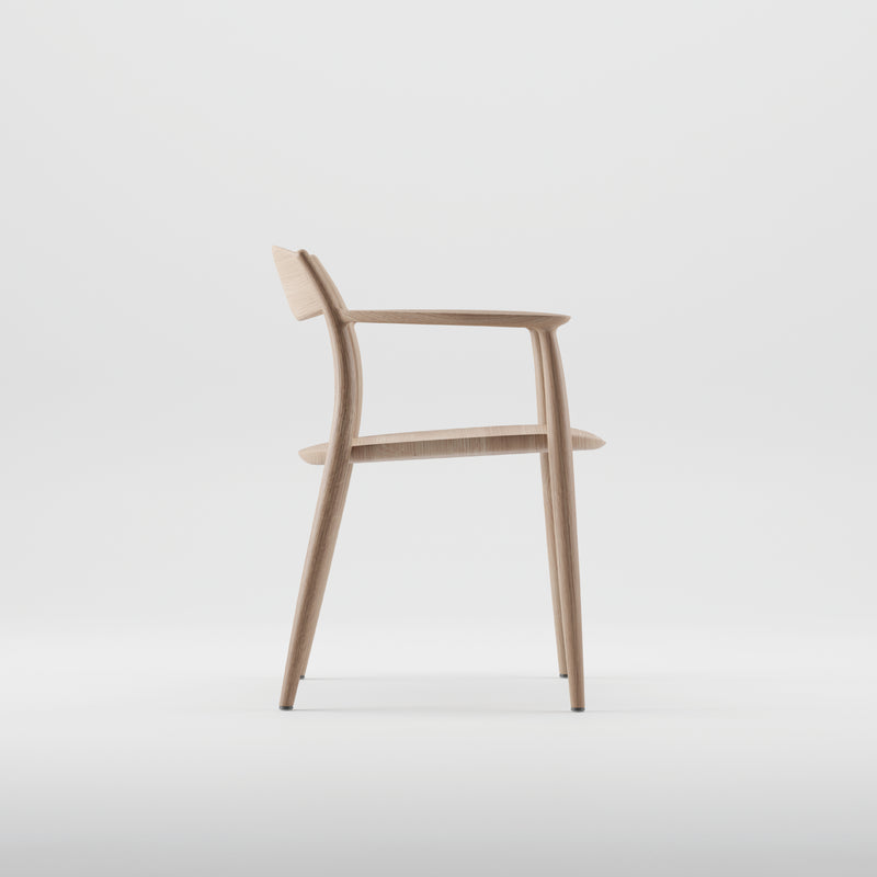 The NILA Chair by Artisan is a minimalist wooden chair with a sleek design, featuring a curved backrest and armrests. Crafted from solid wood with natural oils, it embodies eco-friendly elegance, showcasing its modern sophistication against a plain white background.
