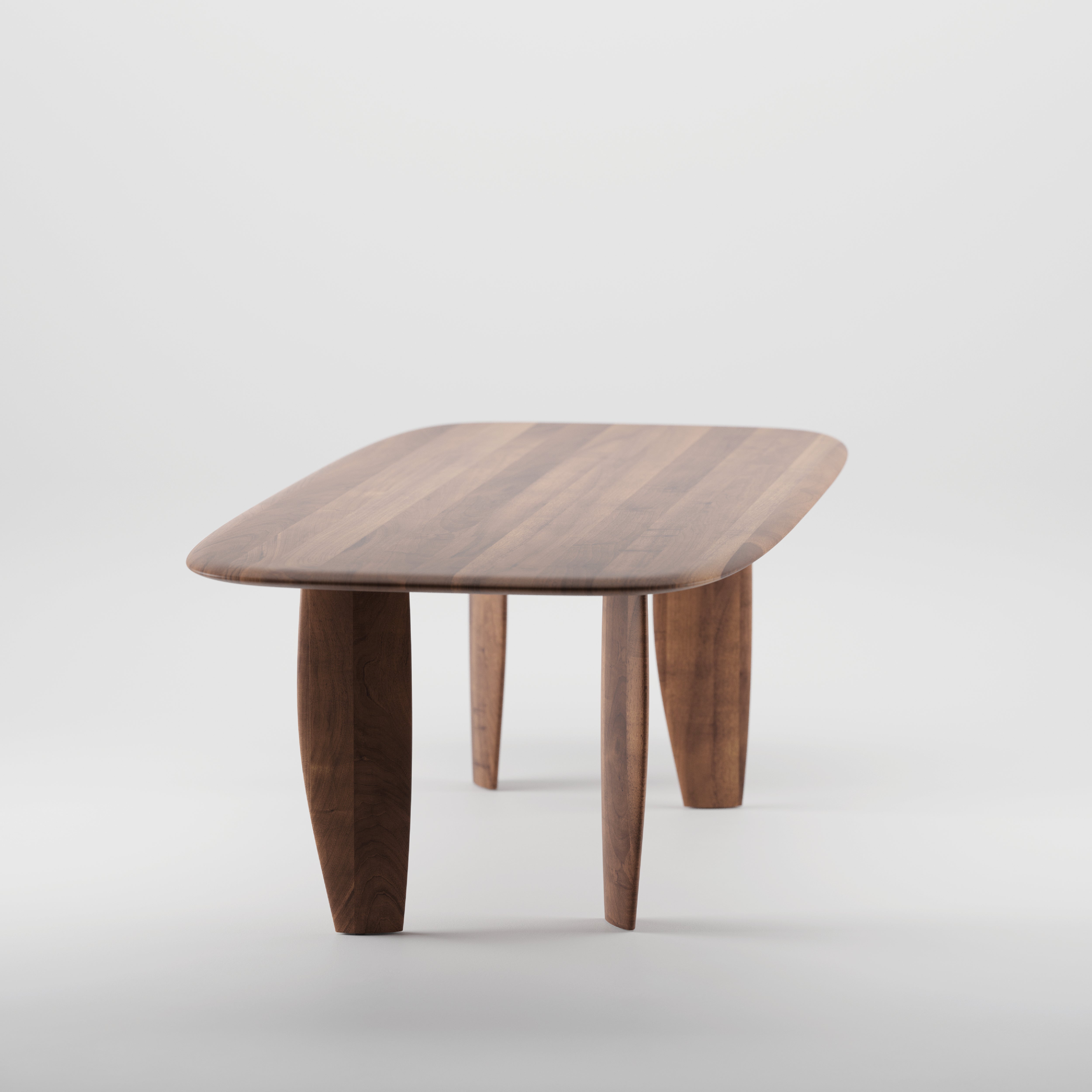The NILU Table by Artisan is a wooden table with a sleek rectangular design, rounded corners, and slightly curved legs. Its crafted from solid wood, finished with natural oils to highlight its elegant grain pattern, and its eco-friendly.