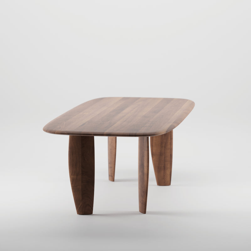 The NILU Table by Artisan is a wooden table with a sleek rectangular design, rounded corners, and slightly curved legs. Its crafted from solid wood, finished with natural oils to highlight its elegant grain pattern, and its eco-friendly.