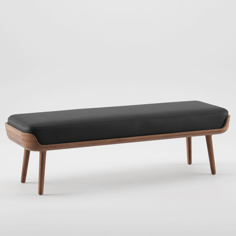 The THOR Bench by Artisan is a modern, minimalist piece crafted from solid wood, featuring a sleek black cushion. Its natural texture and four sturdy legs stand out on a white background, highlighting the beauty of eco-friendly materials.