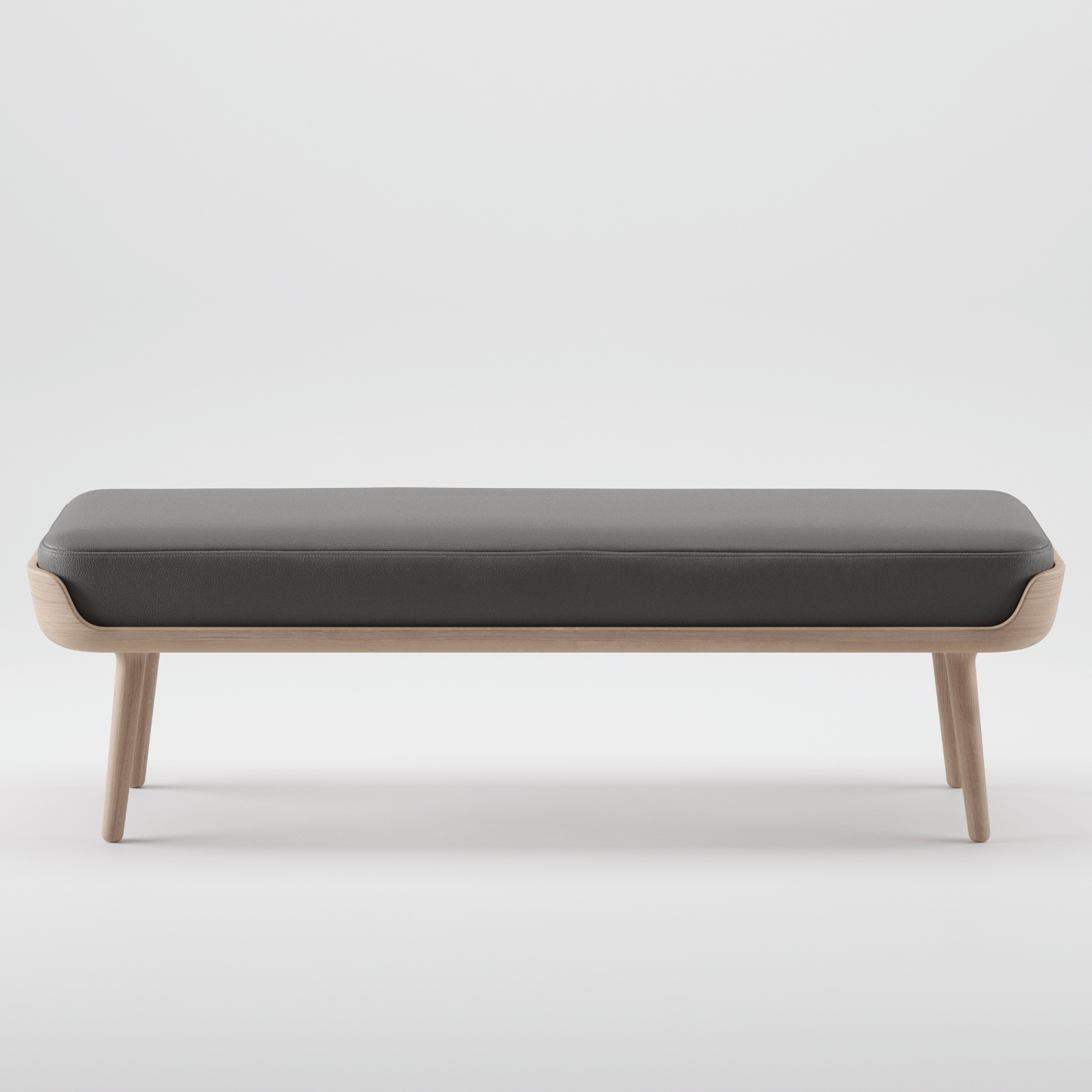 The THOR Bench by Artisan presents a modern, simple design with a dark cushioned seat on a light wooden frame, accentuating the natural wood texture. Made from solid, eco-friendly materials, it stands elegantly on four legs against a white background.