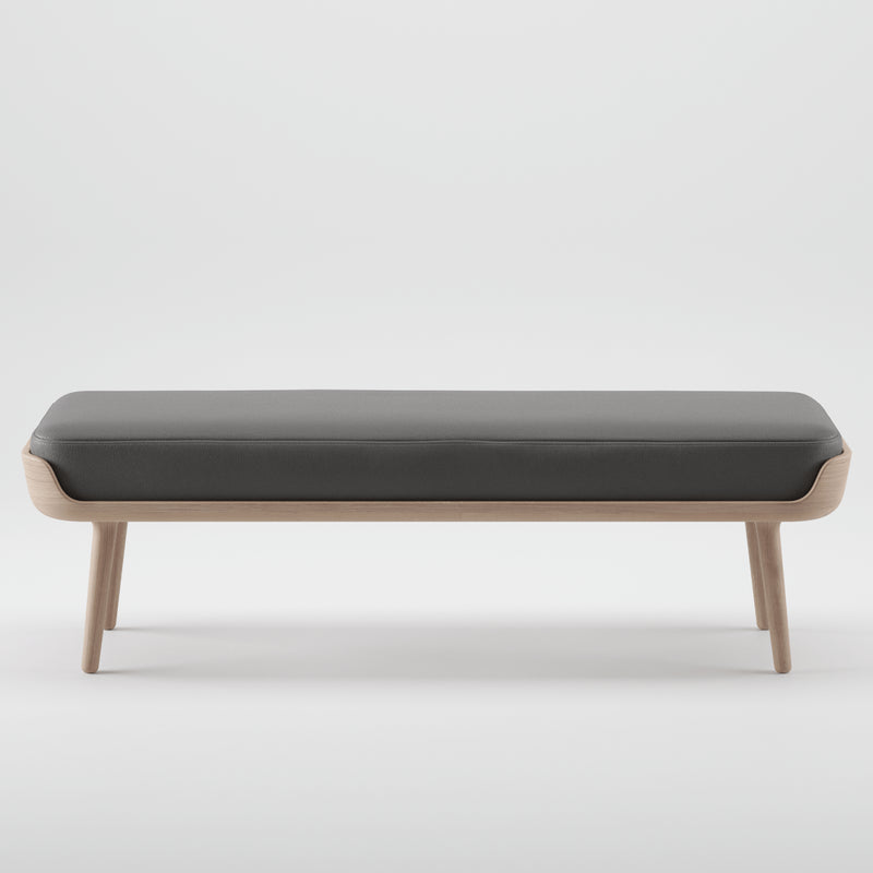 The THOR Bench by Artisan presents a modern, simple design with a dark cushioned seat on a light wooden frame, accentuating the natural wood texture. Made from solid, eco-friendly materials, it stands elegantly on four legs against a white background.