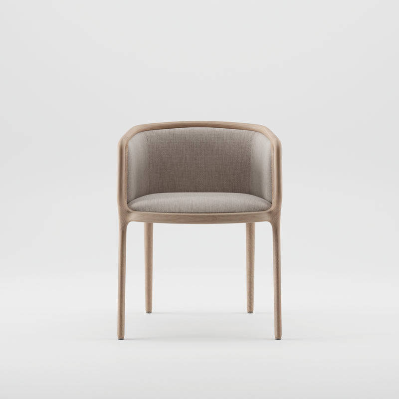 The VELO Chair by Artisan boasts a minimalist design with a light brown wooden frame showcasing natural texture. Its beige upholstered seat and backrest feature a curved back flowing into armrests, supported by four slender legs made from eco-friendly materials, all set against a plain white background.