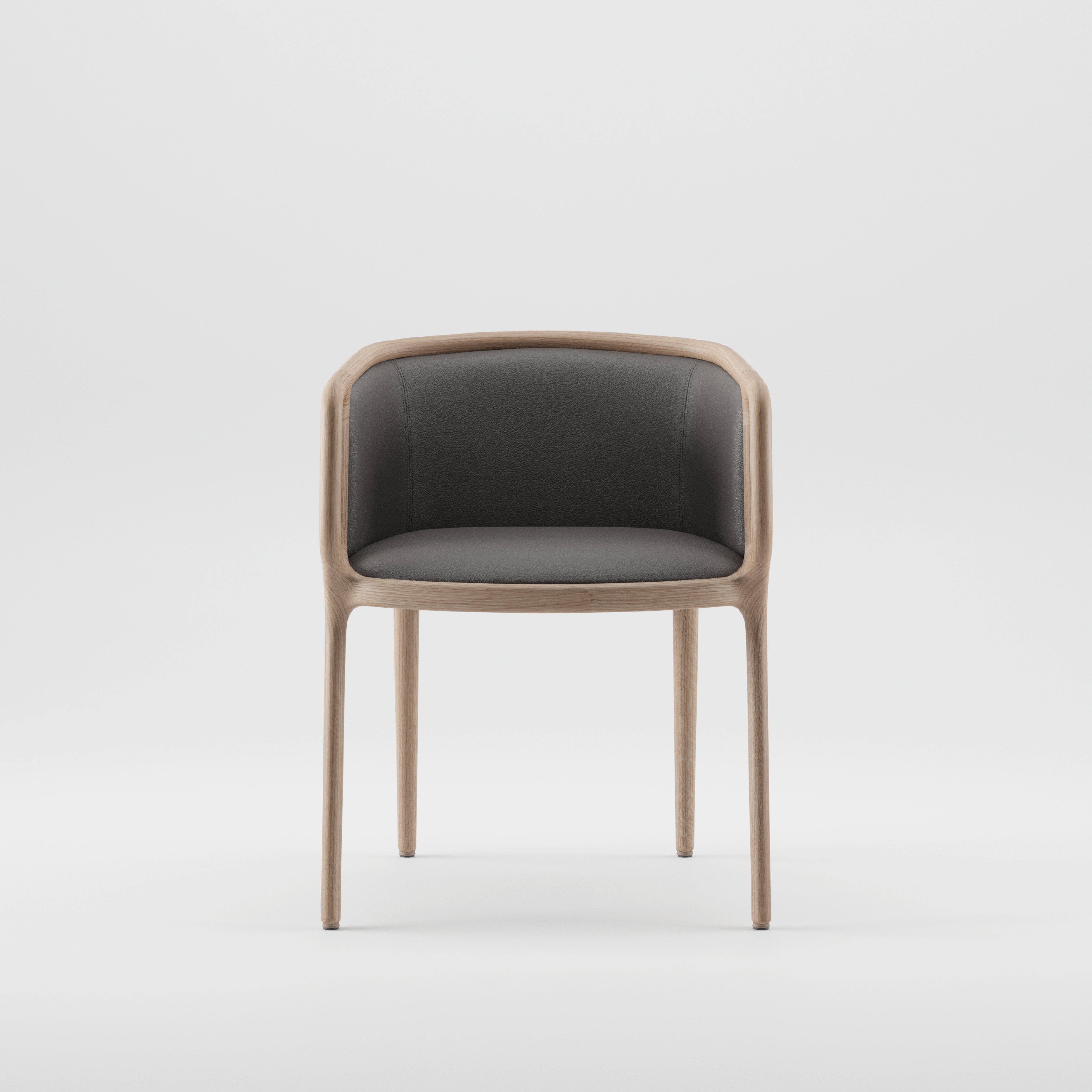 The VELO Chair by Artisan is a minimalist solid wood chair with a light frame and dark cushioned seat and backrest. Its rounded design, four slender legs, and eco-friendly materials make it a sustainable choice that complements any space effortlessly.
