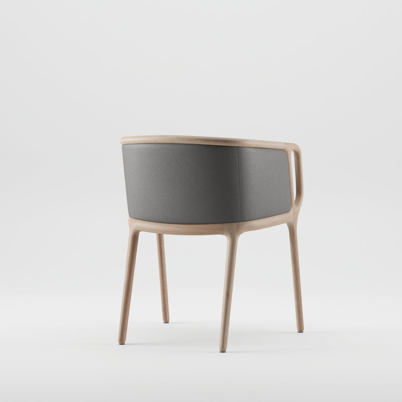 The VELO Chair by Artisan is presented from the back, showcasing a solid wood frame and gray fabric upholstery. Made with eco-friendly materials, it features a curved backrest and slender legs for a sleek, minimalist style against a white background.