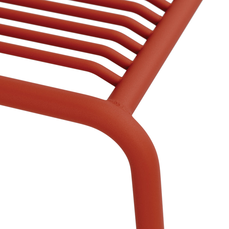 Close-up of the IVY Outdoor Stool by Objekte unserer Tage, featuring a corner of its red powder-coated steel design. Its curved tubular bars create an ergonomic seat, ideal for modern and minimalist outdoor furniture.