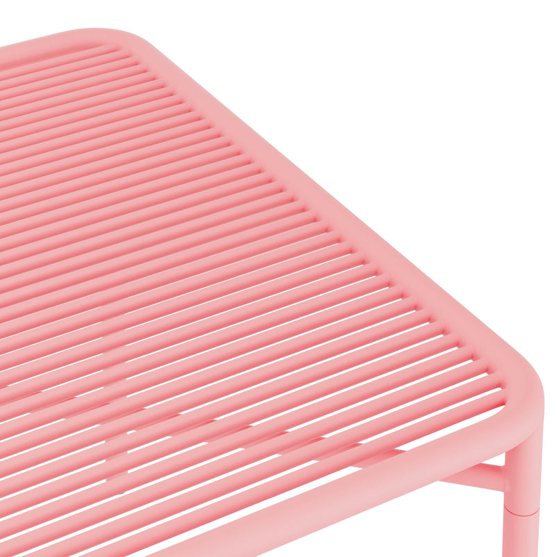 A close-up of the IVY Outdoor Table by Objekte unserer Tage showcases its pink, slatted design with parallel bars, crafted from powder-coated steel. The image highlights its modern, minimalist style with a focus on the tables top and legs.