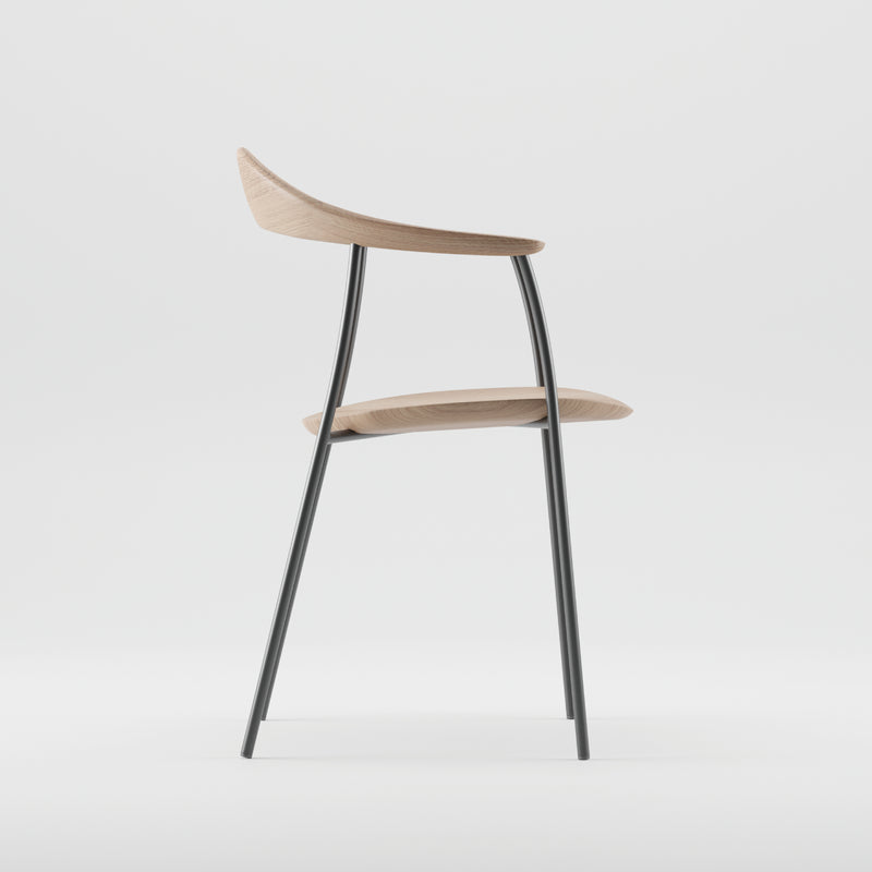 Side view of the NEVA contour chair by Artisan, showcasing a modern design with a curved wooden seat and backrest crafted using CNC carving. The chair has slender black metal legs and is set on a plain white background, embodying the essence of minimalism.