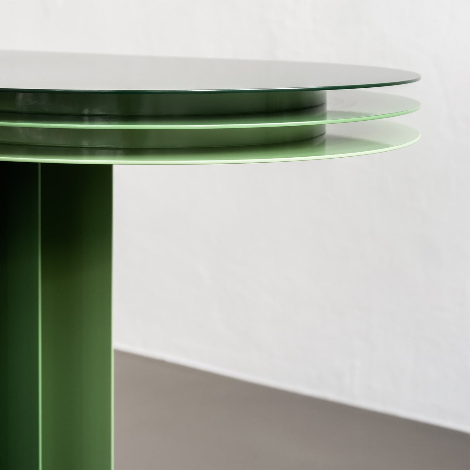 This sleek green table, crafted from powder-coated steel, features three stacked circular layers on a neutral backdrop. The glossy tabletop enhances visual depth and its minimalist modern design complements the Victor Foxtrot My Ami Sideboard perfectly.