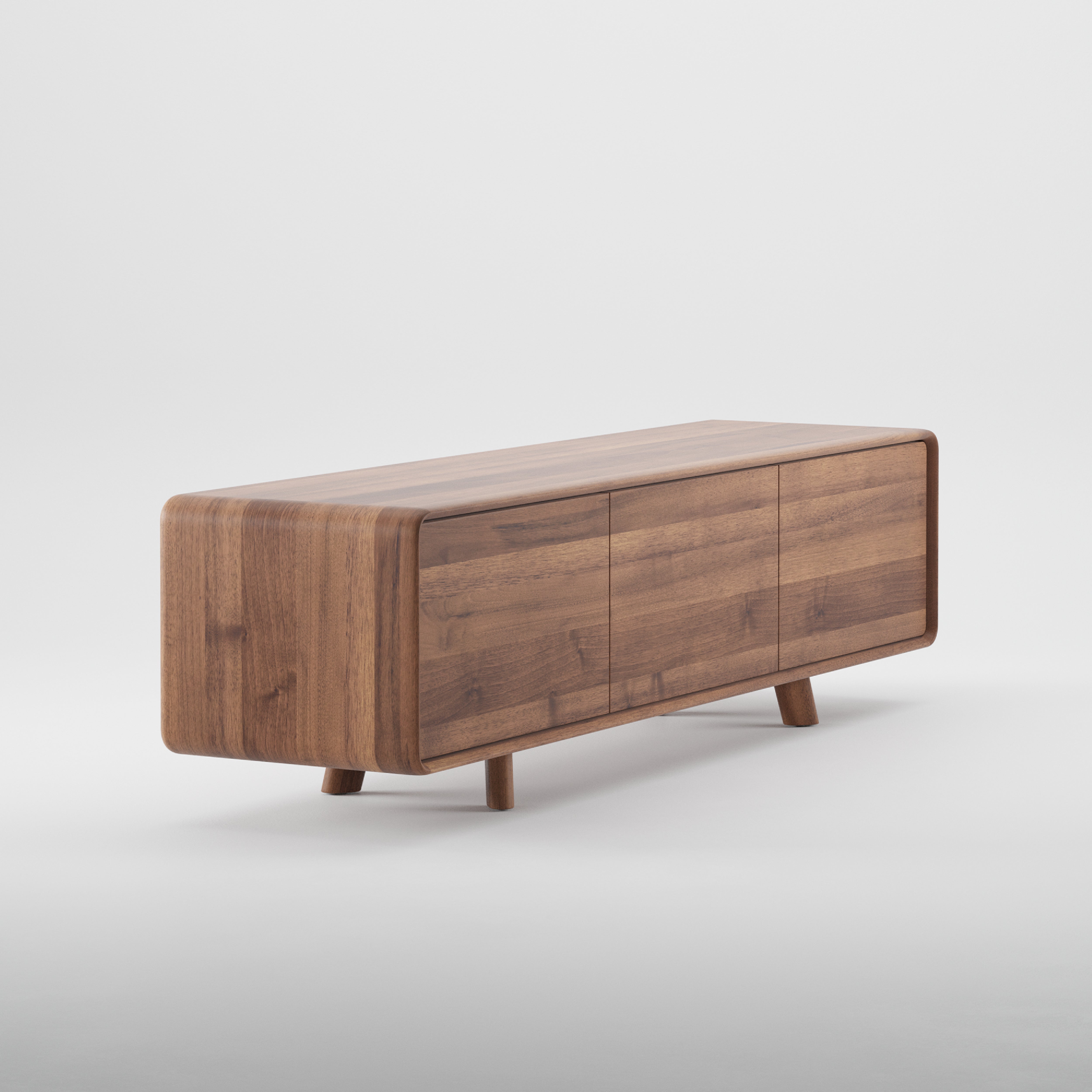 The NEVA Lowboard by Artisan is a stylish wooden sideboard with a minimalist design. Crafted from solid wood, it features a smooth, rounded rectangular shape with three cabinet doors. Sturdy legs and a natural wood grain finish are enhanced by eco-friendly oils against a plain white background.