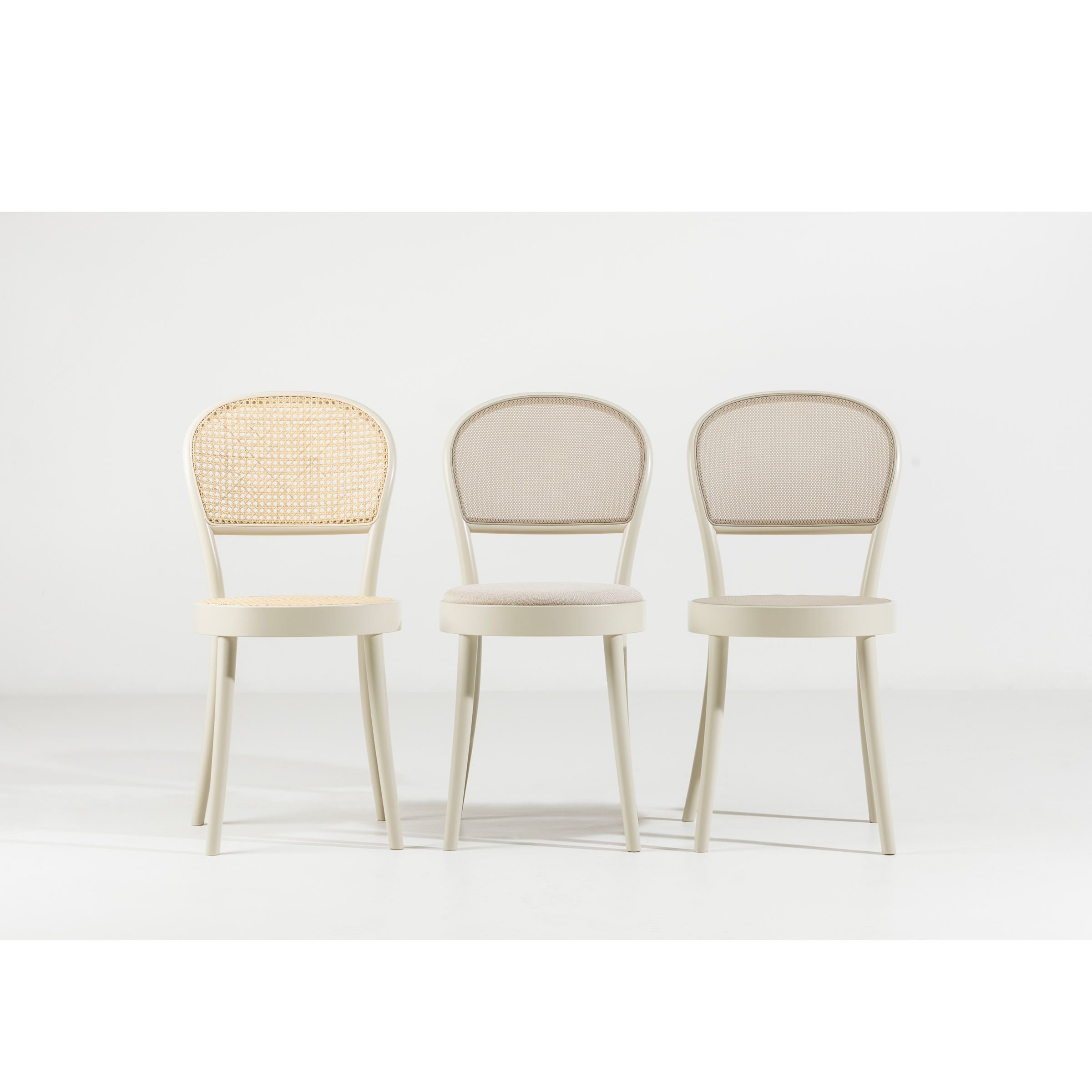 Three TON Chair 314-Cane beige chairs are lined up against a plain white background. The left chair features bentwood craftsmanship with a woven cane back, complementing the solid fabric backs of the other two, all sharing simple, elegant designs and wooden legs.