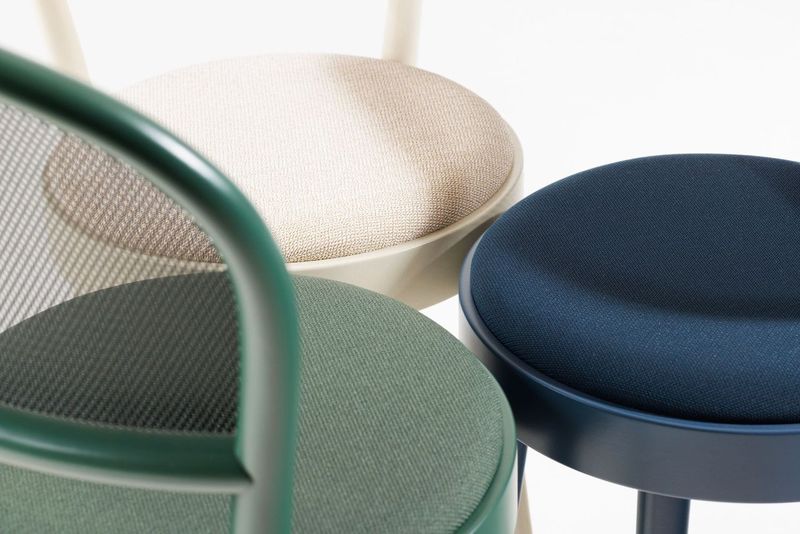 Top view displays three TON Chair 314-Upholstered stools, exemplifying bentwood craftsmanship: one with a textured beige seat and cream frame, another with a dark green seat and matching frame, and the third with a dark blue seat and frame. A true testament to contemporary design by TON.