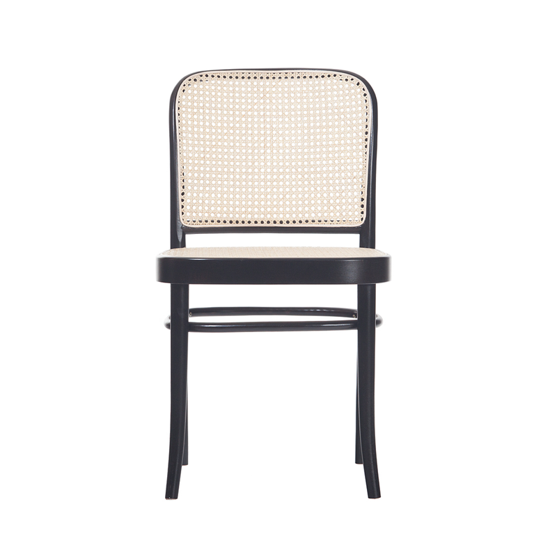 The Chair 811 - Cane by TON, inspired by Josef Hoffmann, showcases a black wooden frame with a beige rattan weave for the backrest and seat. Its four legs offer a classic look, as the textured rattan contrasts elegantly with the sleek frame—a tribute to Art Nouveau style.