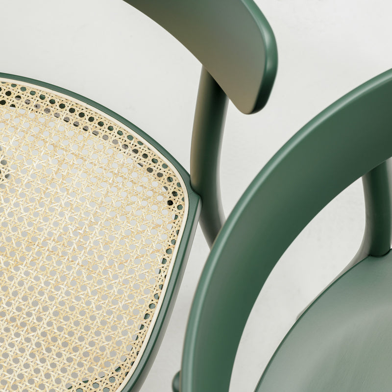 A close-up of the TON Chair La Zitta - Cane reveals its ergonomic design with a rounded wooden backrest and woven cane seat. The view from above emphasizes its solid wood construction and intricate details against a neutral backdrop.