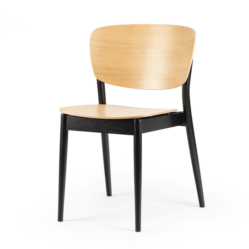 The Chair Valencia by TON is a modern dining chair with a light wood seat and backrest, featuring solid wood construction. It has black legs and a minimalist design, blending natural tones with sleek black elements for an ergonomic touch.