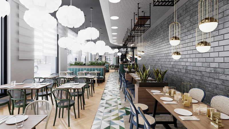 The modern restaurant interior showcases contemporary design with a mix of TON Chair 314-Cane and cushioned seating around tables set with plates and glasses. Pendant lights hang above a patterned floor, accented by plants along a brick wall, creating a bright and spacious ambiance.