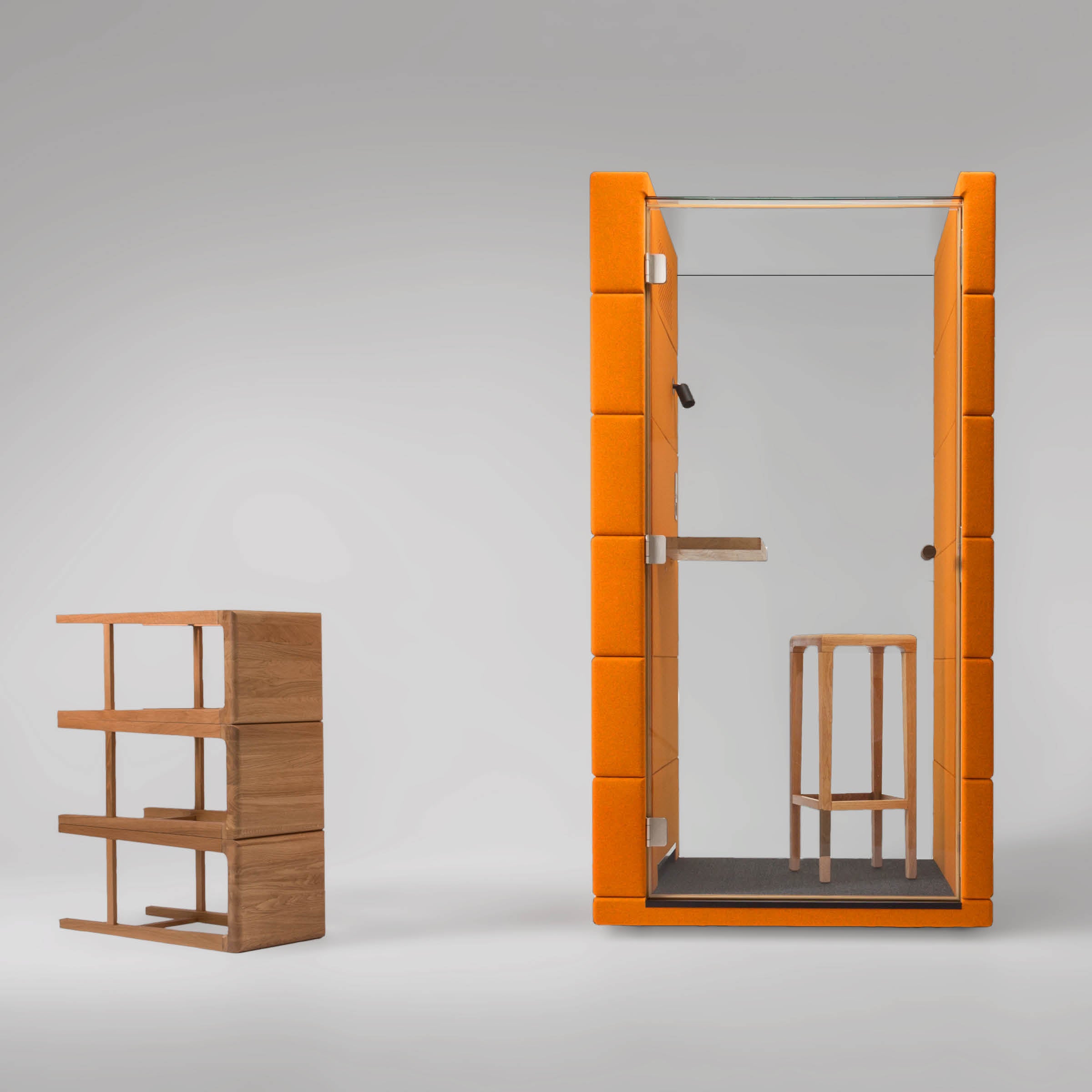 The OFFICE POD UNIQ by SilentLab is a tall, orange structure with a glass door, wooden stool, and is next to a small wooden shelf. Designed for privacy, it offers a quiet workspace with soundproofing and acoustic upholstery on a plain gray backdrop.