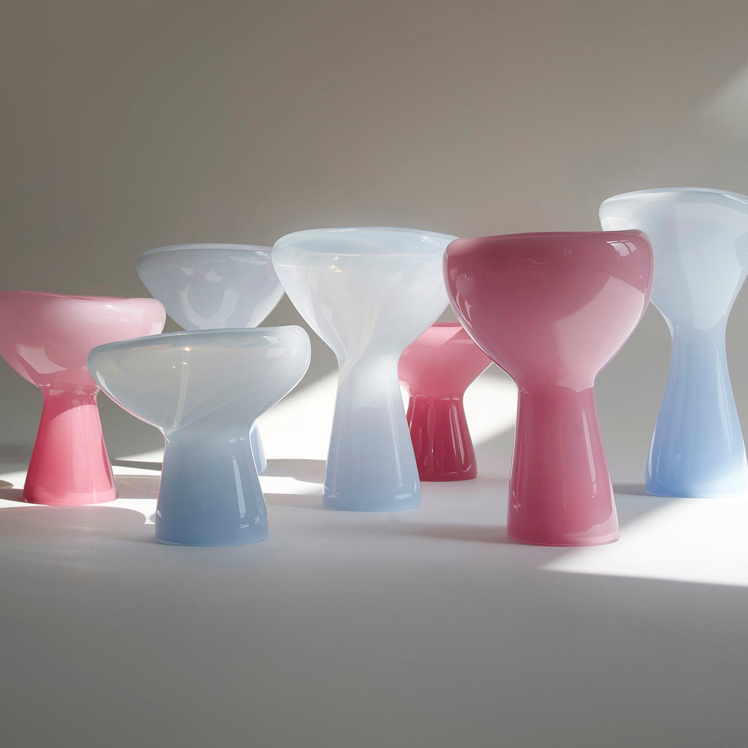 Ursula Futuras PHANTOM Dish features mouth-blown glass sculptures in white, pink, and light blue. Reminiscent of oversized chess pieces with bulbous shapes, their glossy design casts soft shadows on pristine surfaces under natural light.