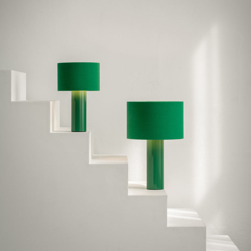 Victor Foxtrots ALL ROUND table lamps, with wool fabric shades and powder-coated steel bases, adorn the ascending white staircase steps. Sunlight casts gentle shadows on the minimalist white wall, crafting a serene and modern ambiance.
