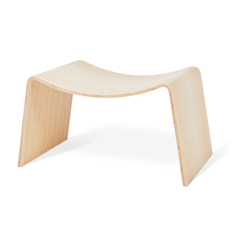 Minimalist light wood stool with curved seat and smooth finish on white background