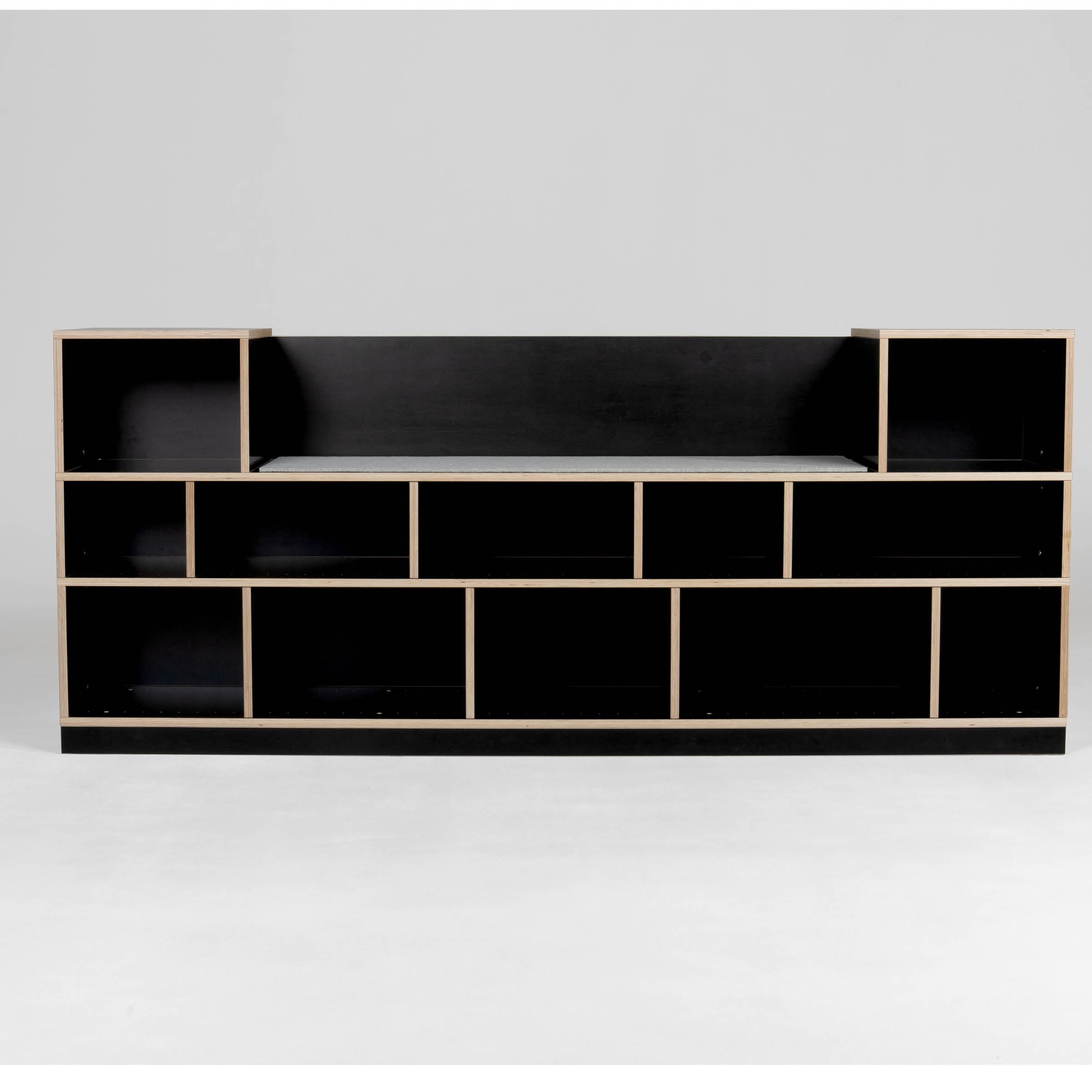 The Egal Sitzboard by Moormann is a modern black bookshelf with a geometric design, featuring customizable open rectangular shelves of varying sizes arranged symmetrically. Light-colored edges contrast the black surfaces, offering style and functionality similar to a refined sideboard.