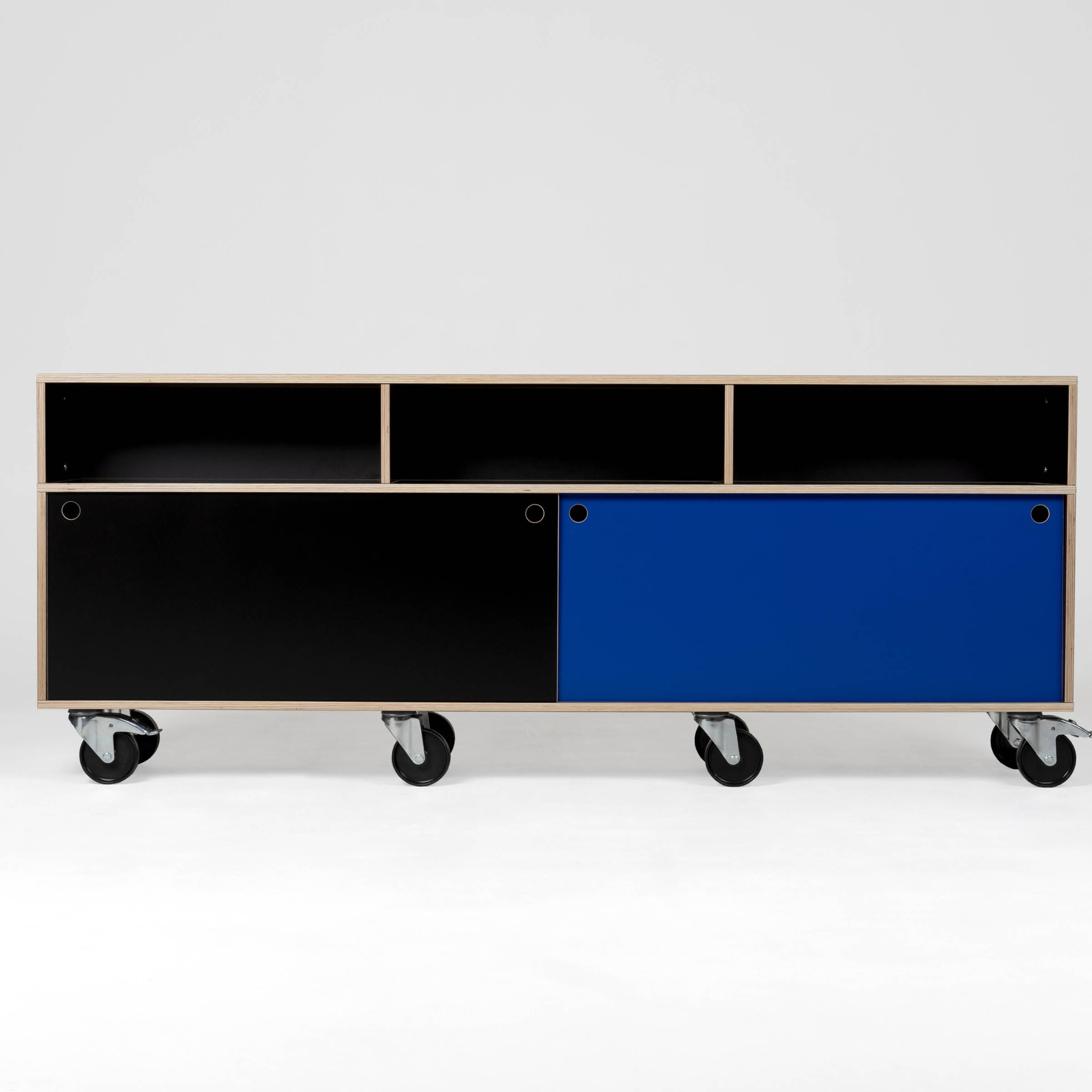 The Egal Rollboard by Moormann is a modern industrial cabinet with a minimalist design, featuring open compartments and black and blue sliding doors. Like the Egal shelf, its on large caster wheels against a plain white background.