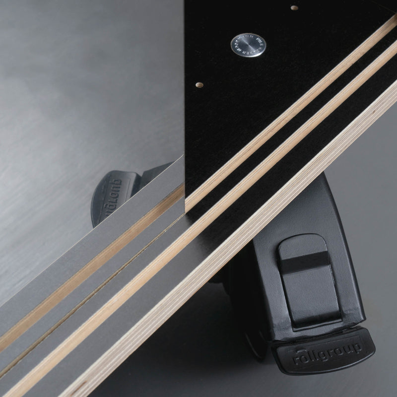 Close-up of Moormanns Egal Rockboard, a geometric piece featuring layered wooden panels and a black metal fixture. A triangular design is accentuated by a visible stainless steel screw against a smooth grey background, exuding modern elegance found in sideboards.