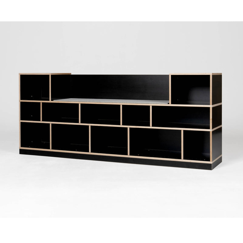The Egal Sitzboard by Moormann is a sleek black modular shelving unit with customizable compartments in a staggered layout, highlighted by a plain white backdrop and light wood edges, elegantly transforming into a versatile sideboard.