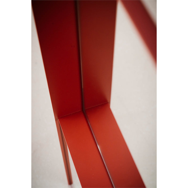 The OneTwo Mirror by Richard Lampert features intersecting red metal beams with a glossy finish, forming a geometric pattern against a soft background. The mirror-like beams reflect light beautifully, offering a modern and industrial touch, perfect as a contemporary home accessory.