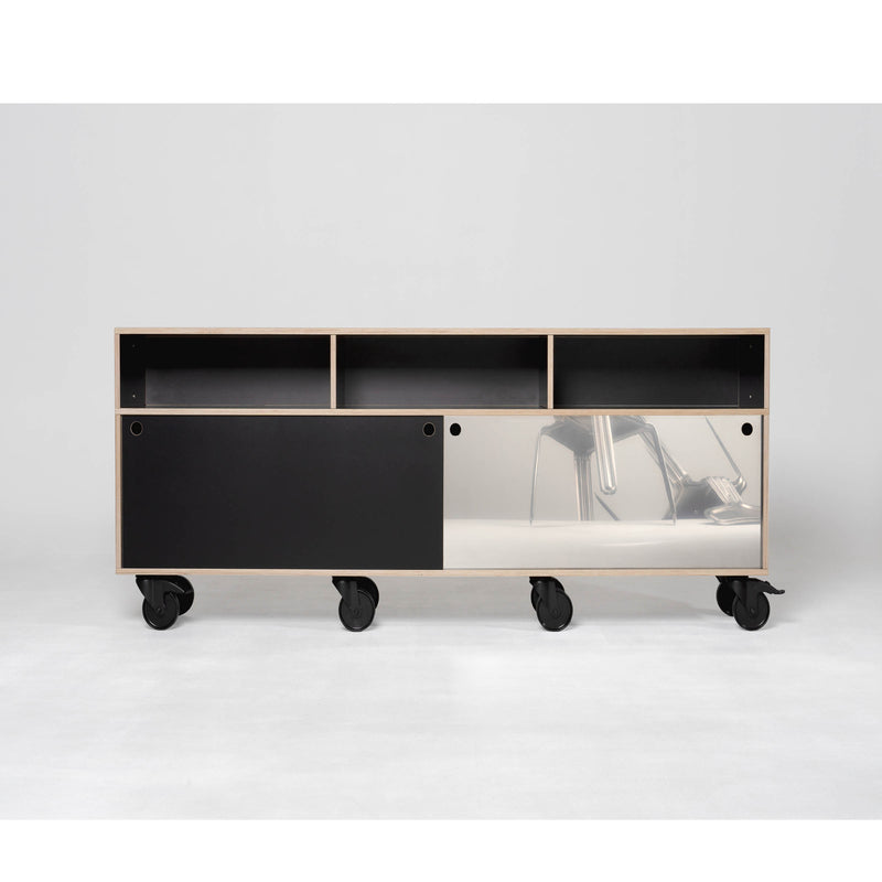 The Moormann Egal Rockboard is a minimalist mobile cabinet with black and reflective panels, featuring sliding doors that reveal open shelves above and enclosed storage below. It sits on stainless steel caster wheels against a plain white background.
