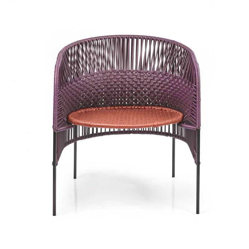 The Ames Caribe Chic Lounge Chair by Ames features a rounded purple woven back, an orange seat, and slender black metal legs, designed to showcase Colombian weaving craftsmanship.