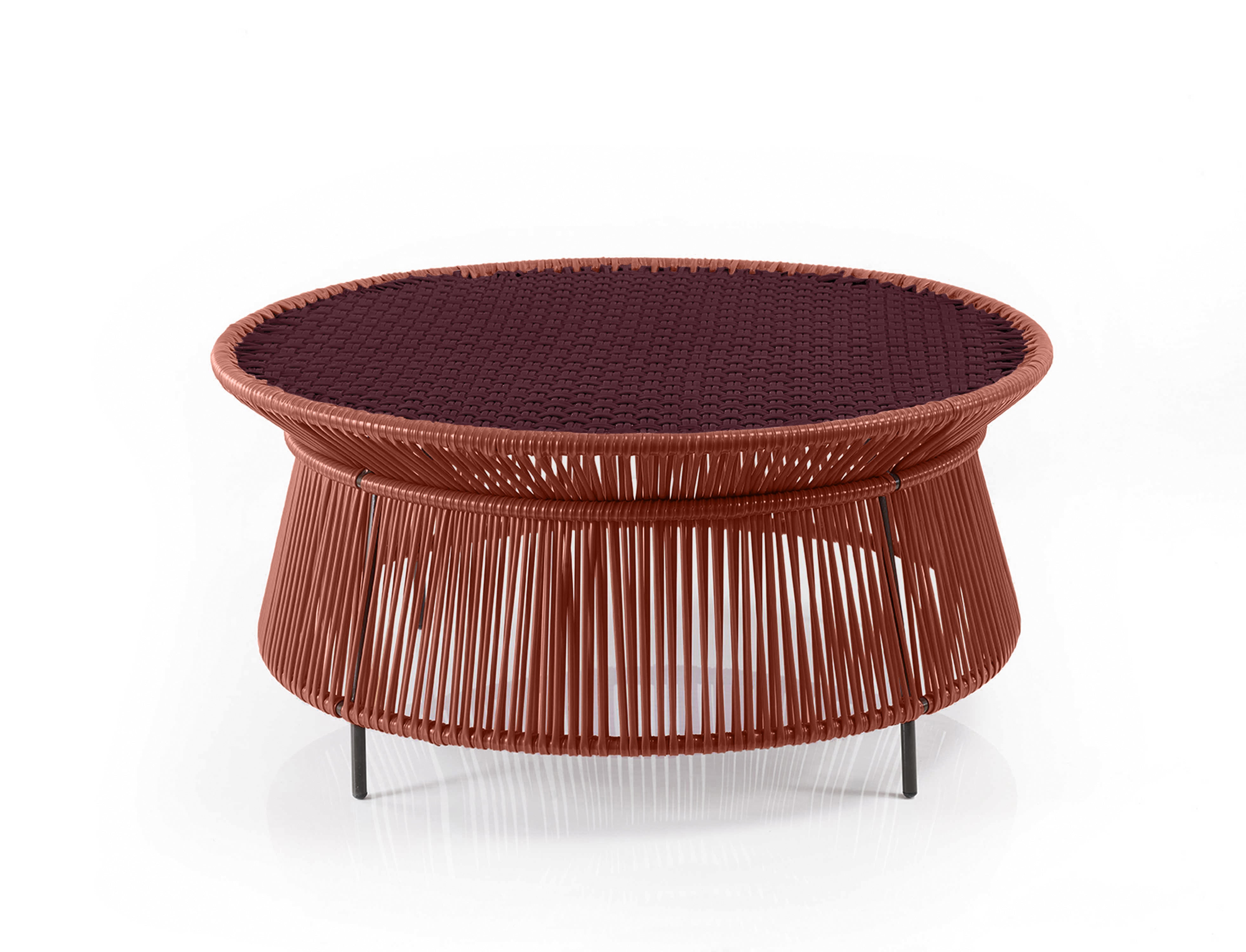 The Ames Caribe Chic Low Table by Ames features a woven reddish-brown frame, slim black legs, and a dark tabletop—an elegant round coffee table designed by Sebastian Herkner to elevate any space.