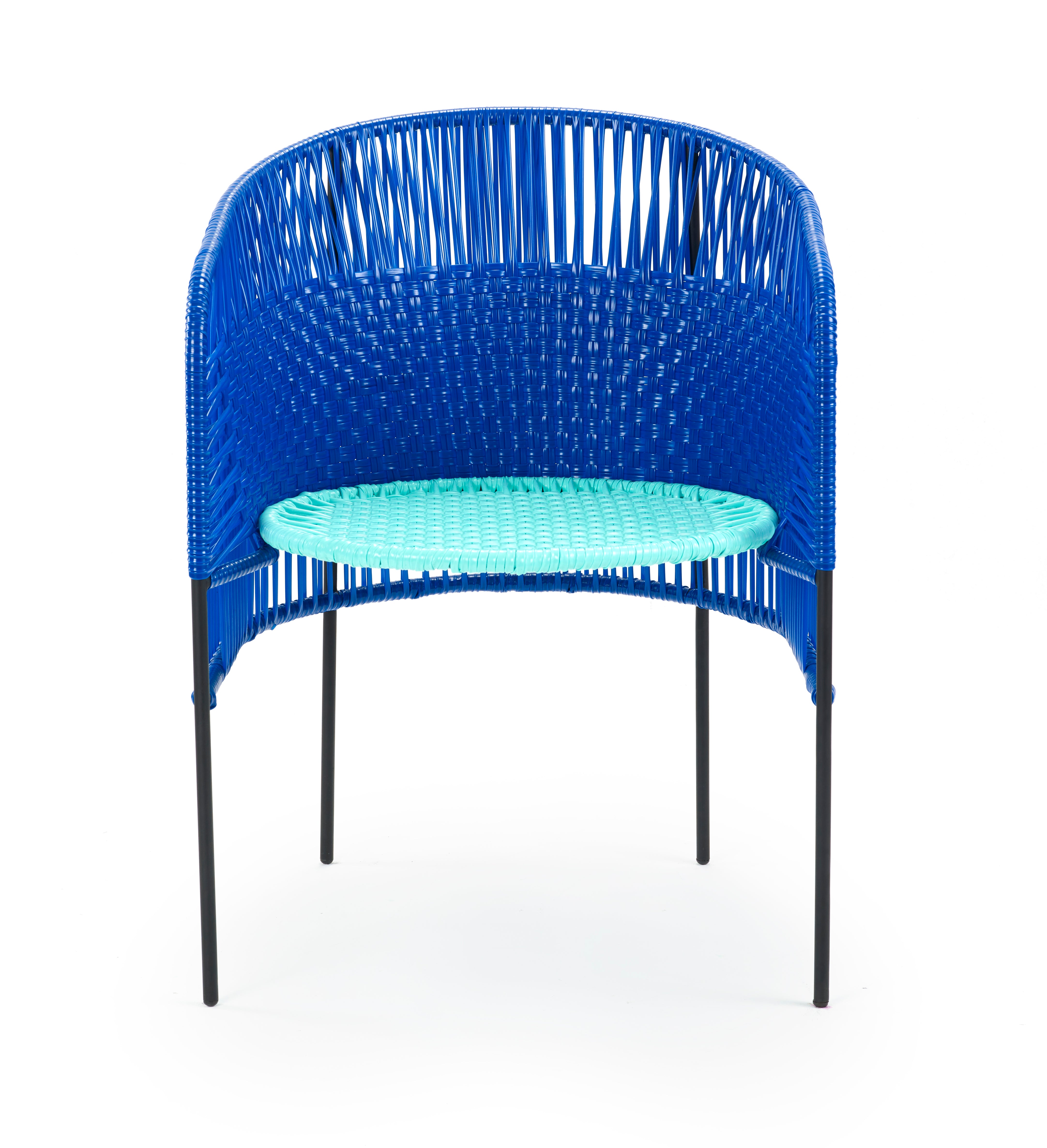 The Caribe Dining Chair by Ames features black metal legs, a rounded backrest with blue Colombian weaving, and a light turquoise woven seat—an eye-catching outdoor piece standing out against a white background.