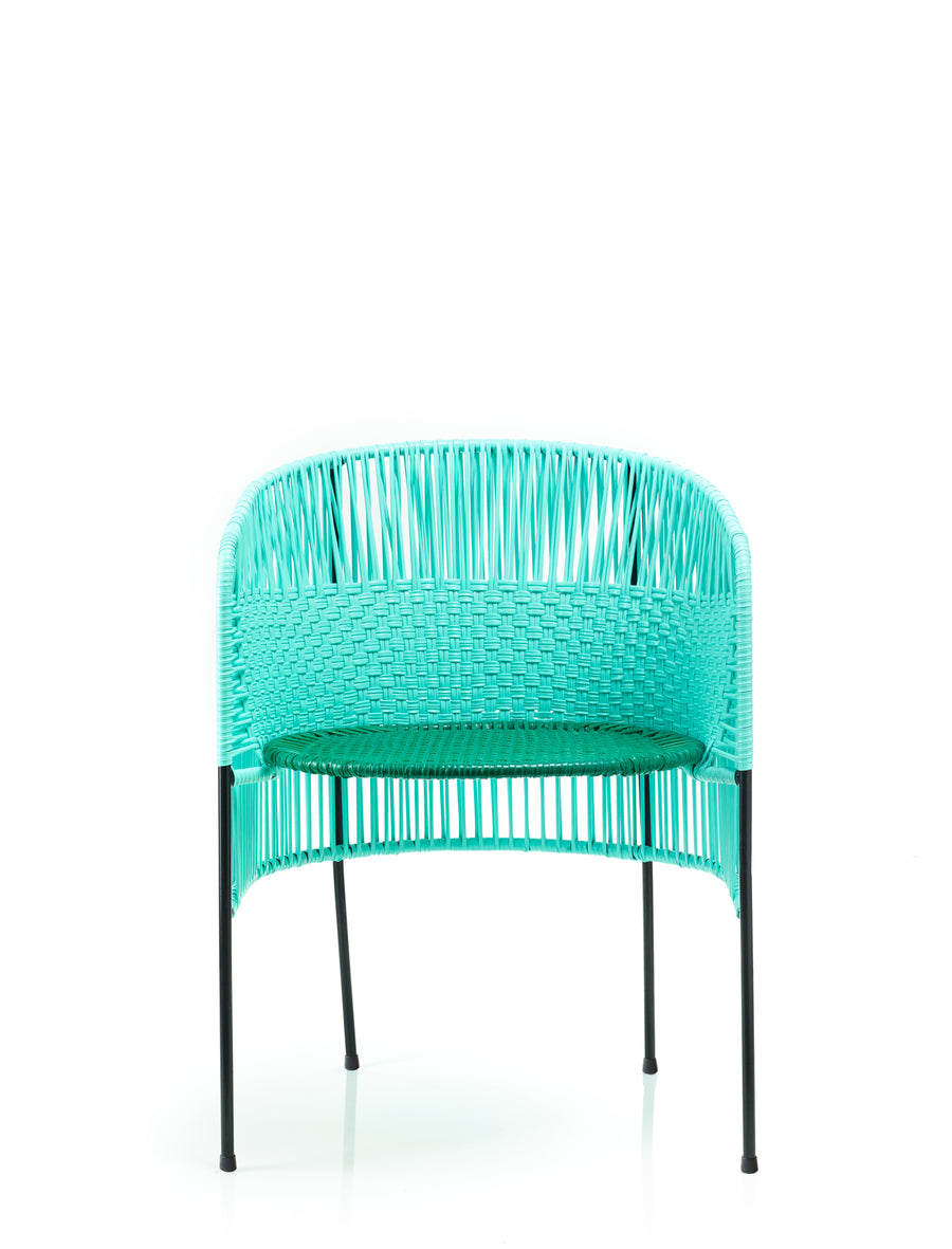 The Caribe Dining Chair by Ames features a modern turquoise woven design with black metal legs, crafted using Colombian weaving techniques. Its rounded back and minimalist look make it ideal for stylish outdoor spaces.